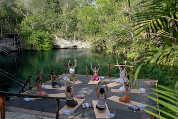 a group of people doing yoga outside by a body of water