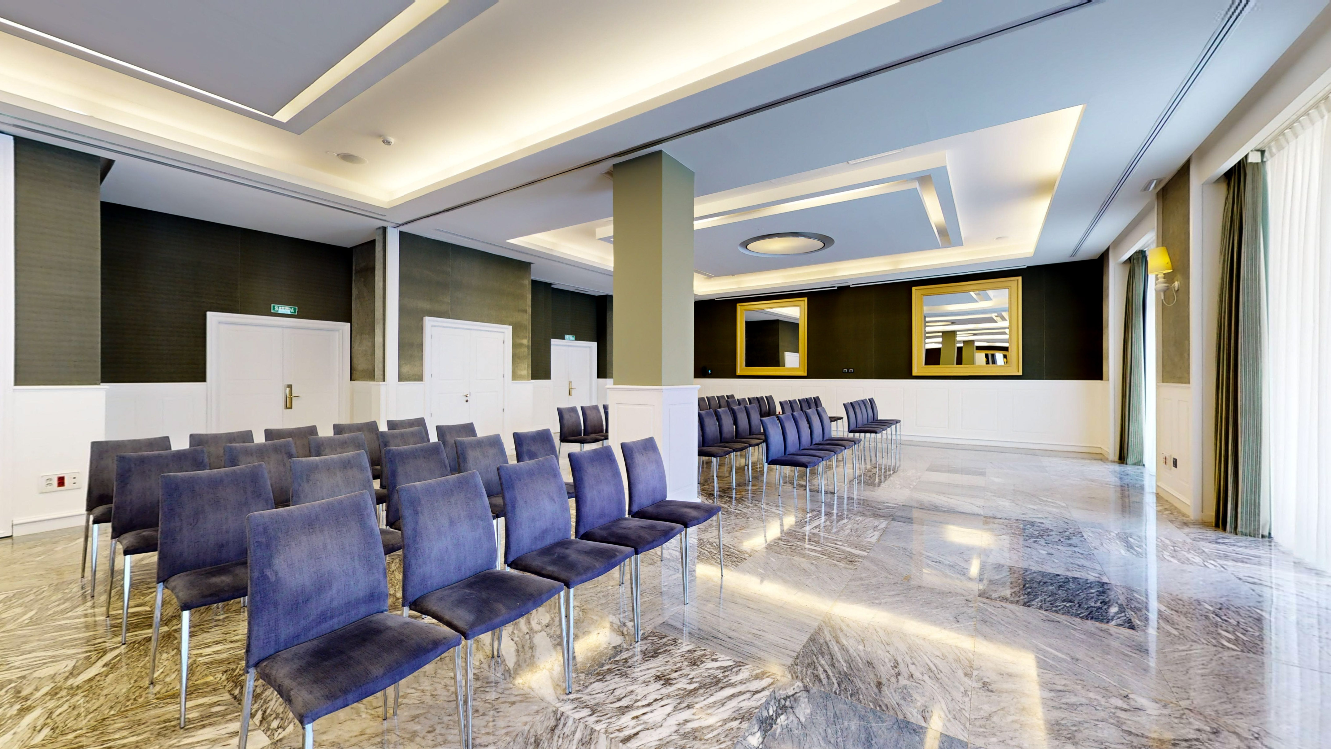 Elegant conference room with blue velvet chairs, marble floor, modern lights.