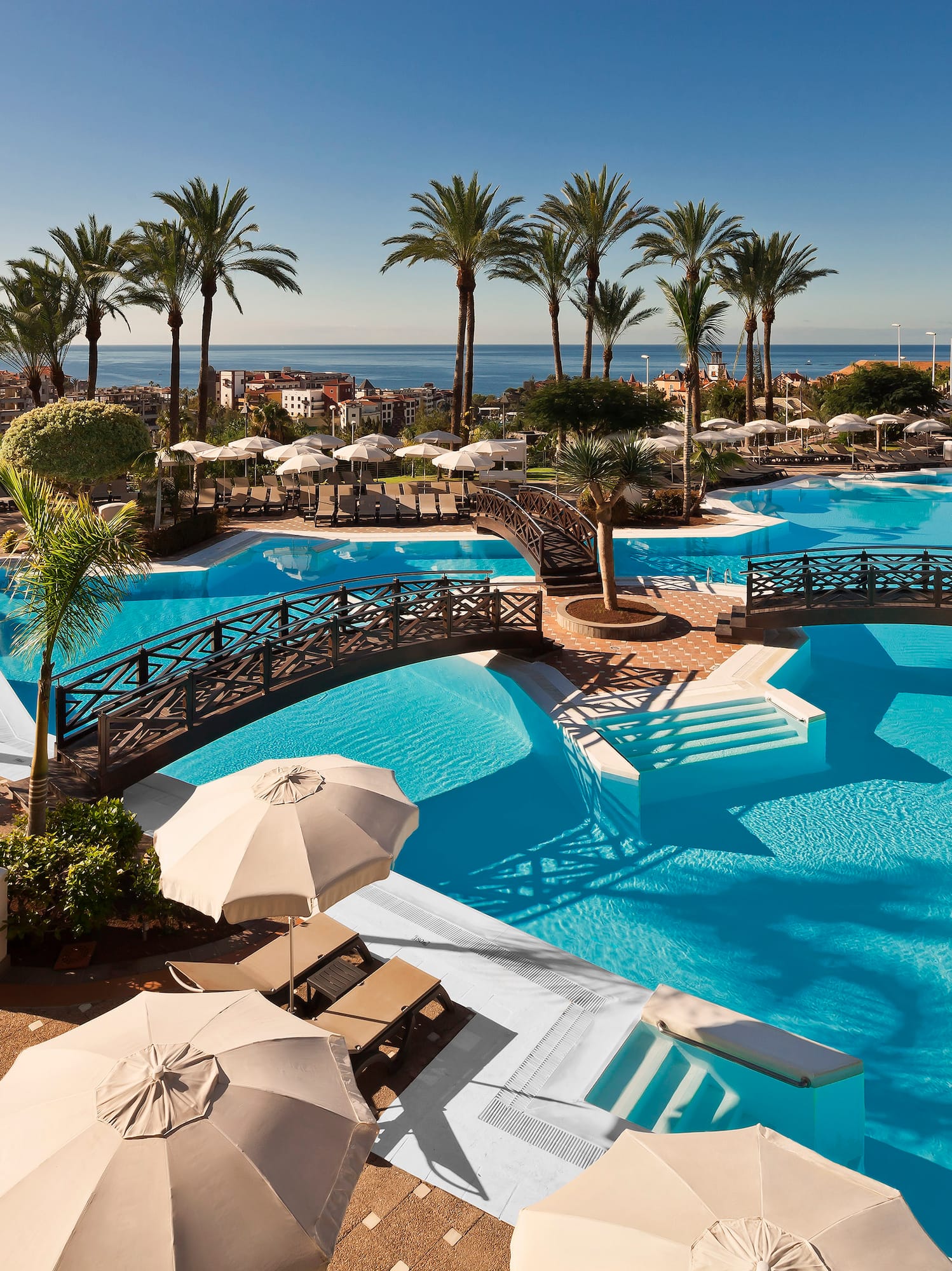 a swimming pool with umbrellas and palm trees
