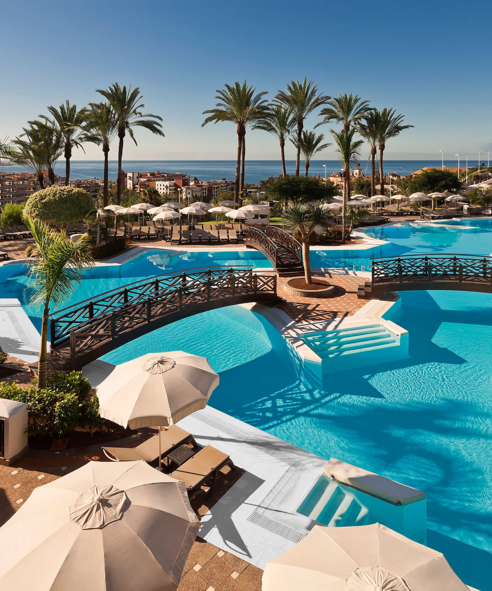 a swimming pool with umbrellas and palm trees