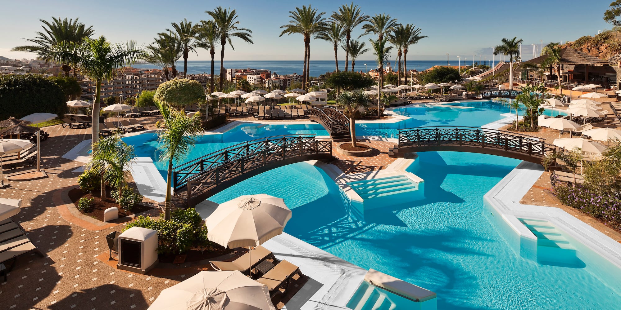 a swimming pool with umbrellas and palm trees