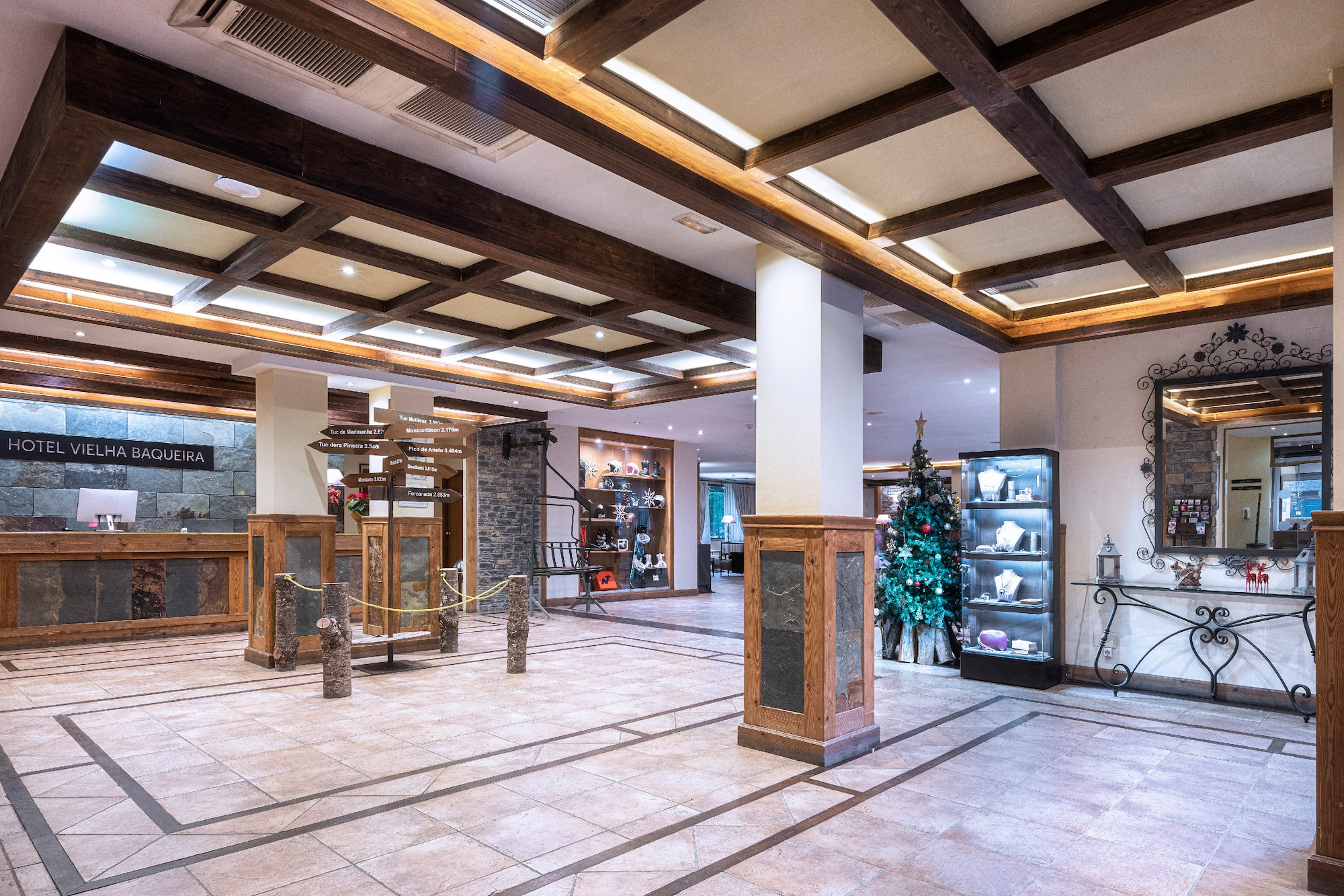 Hotel Vielha Baqueira lobby with rustic wood, stone, and Christmas tree.