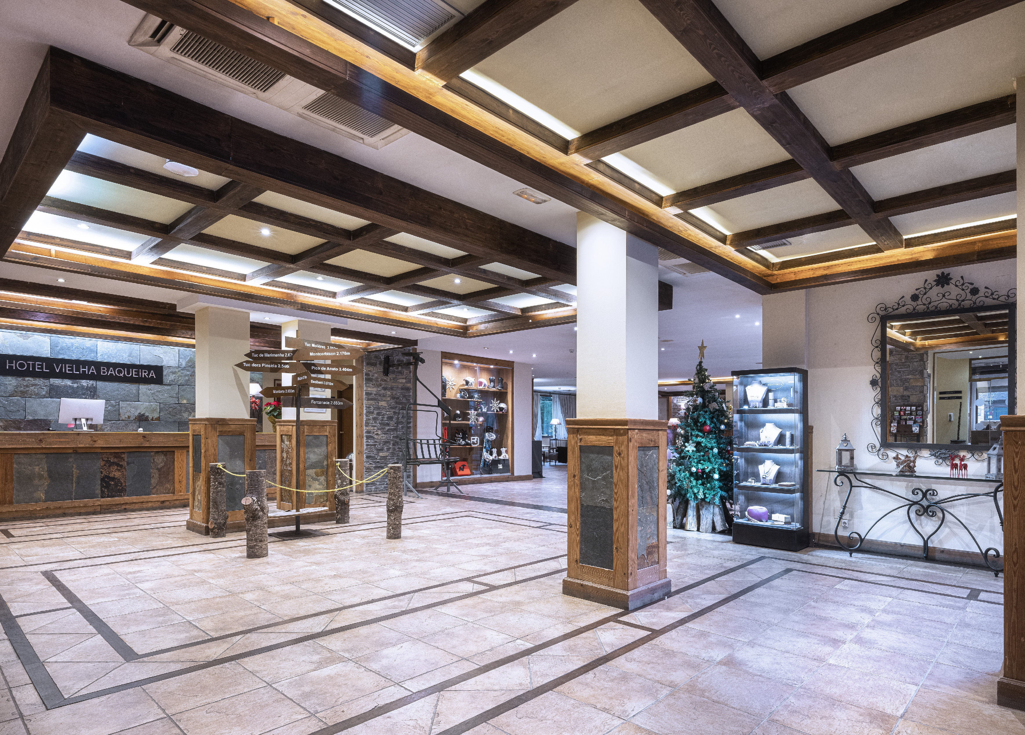 Hotel Vielha Baqueira lobby with rustic wood, stone, and Christmas tree.