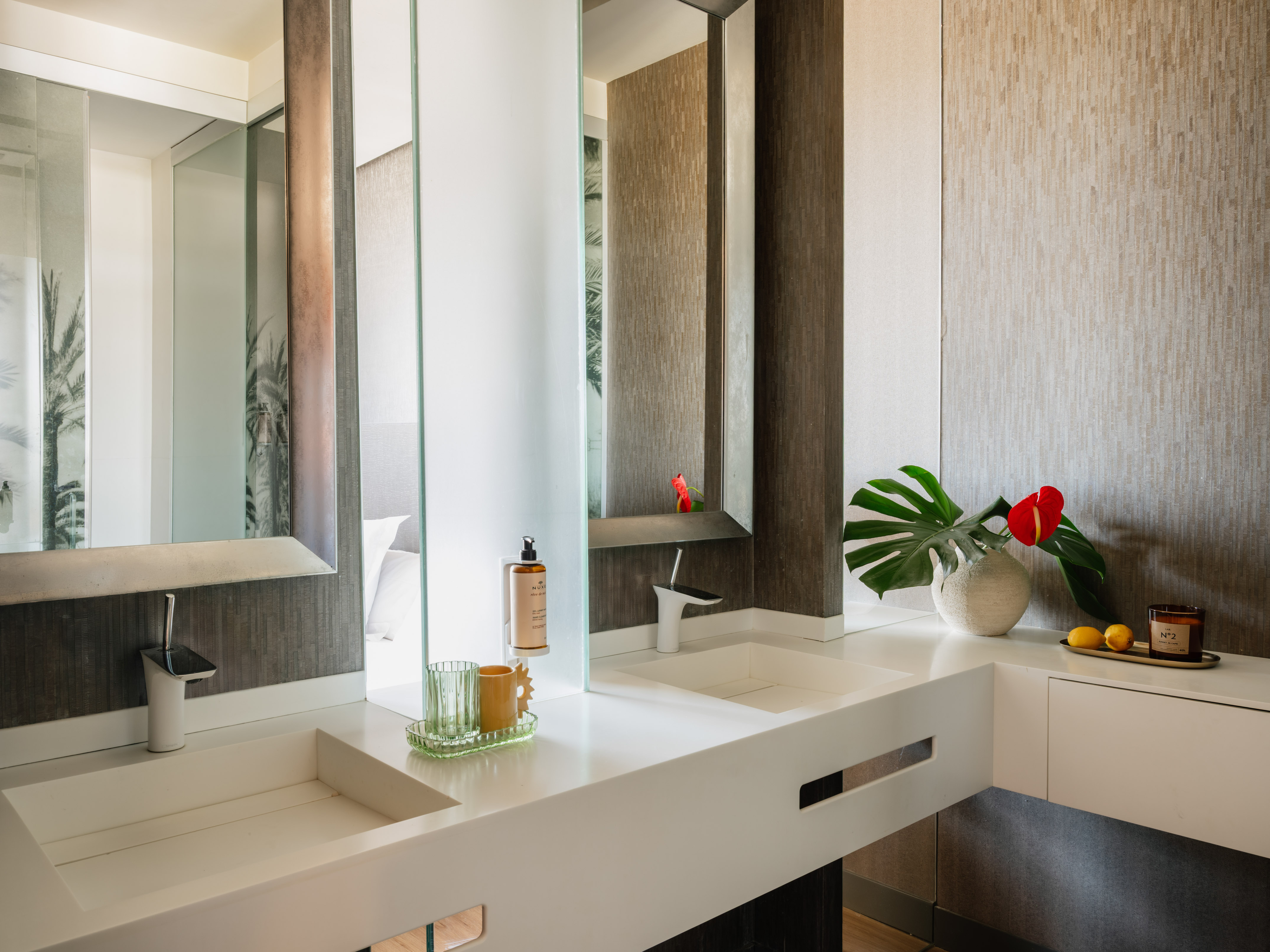 Modern bathroom with double vanity, white sinks, mirrors, tropical accents.