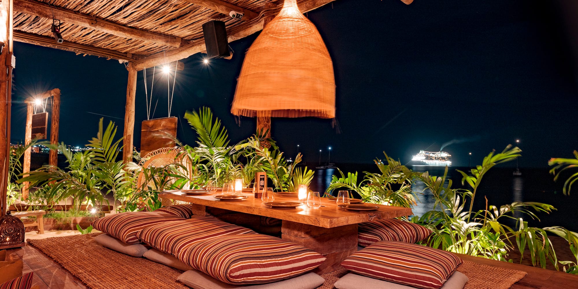 a table with pillows and a lamp on a wooden surface