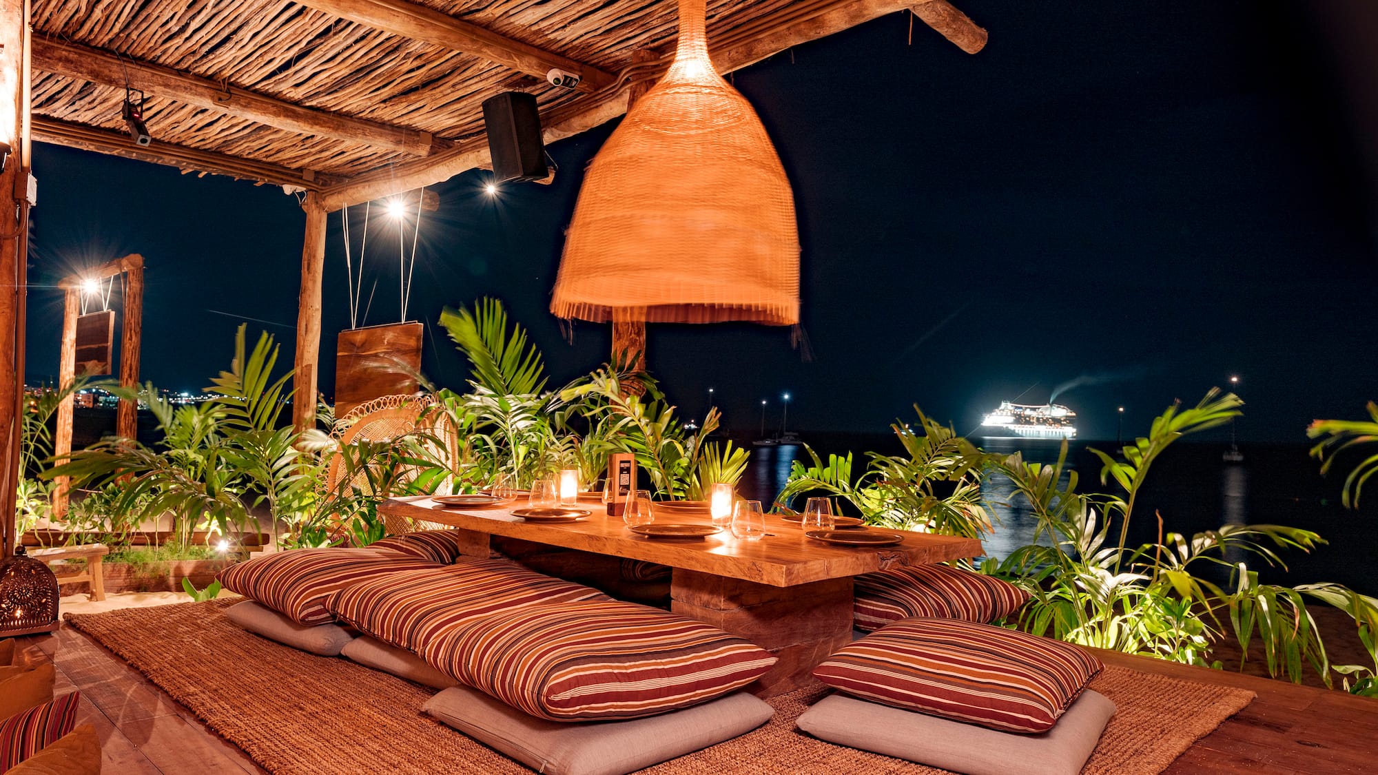 a table with pillows and a lamp on a wooden surface