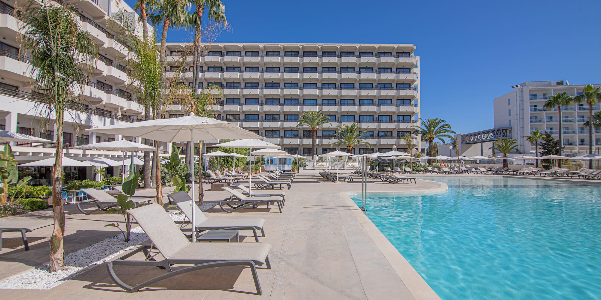 a pool with lounge chairs and umbrellas by a building