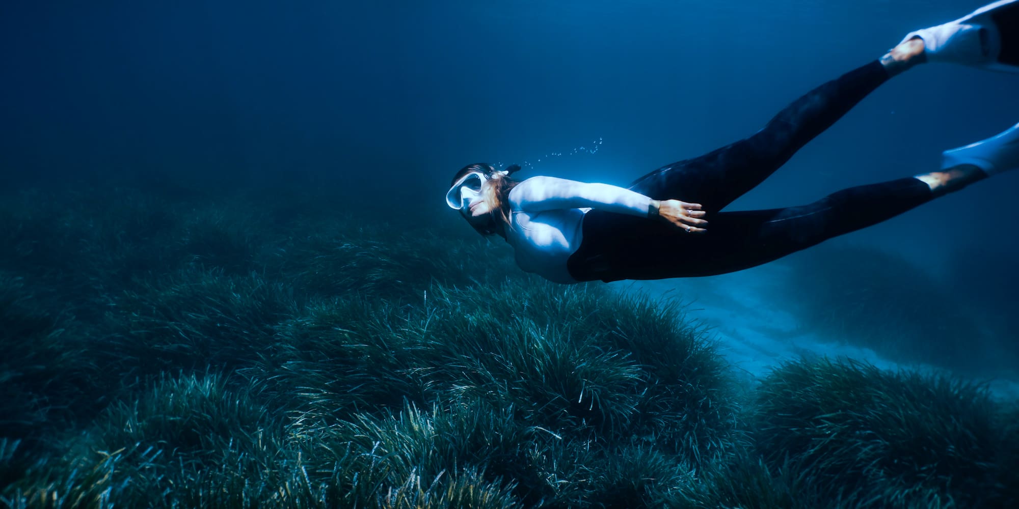 a woman swimming underwater with goggles