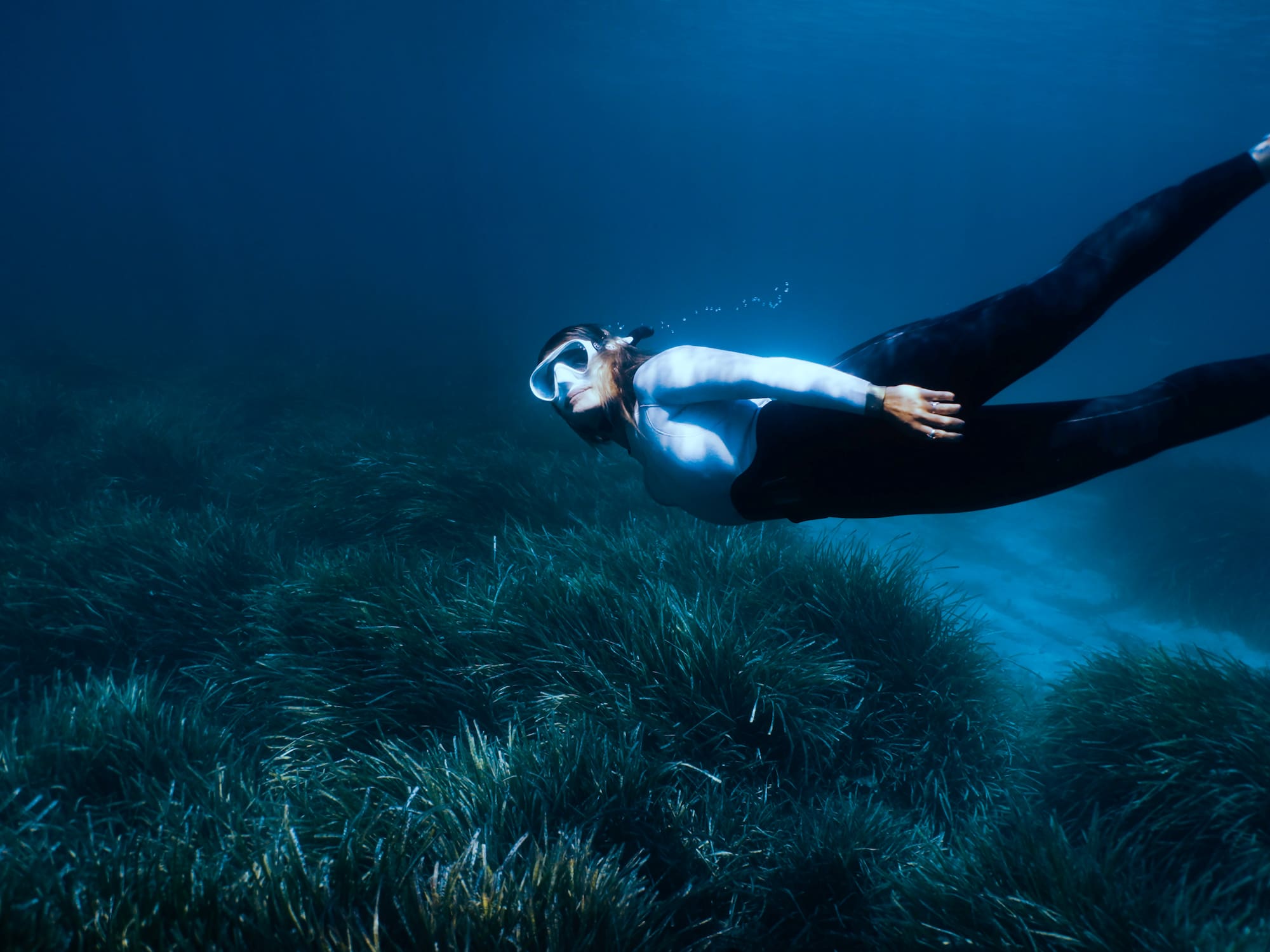 a woman swimming underwater with goggles