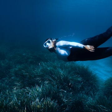 a woman swimming underwater with goggles