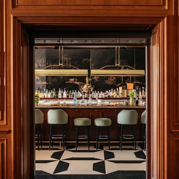 a bar with chairs and bottles in front of it