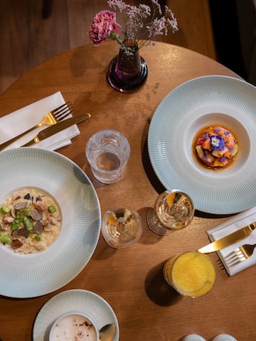 a table with plates of food and glasses and a vase of flowers