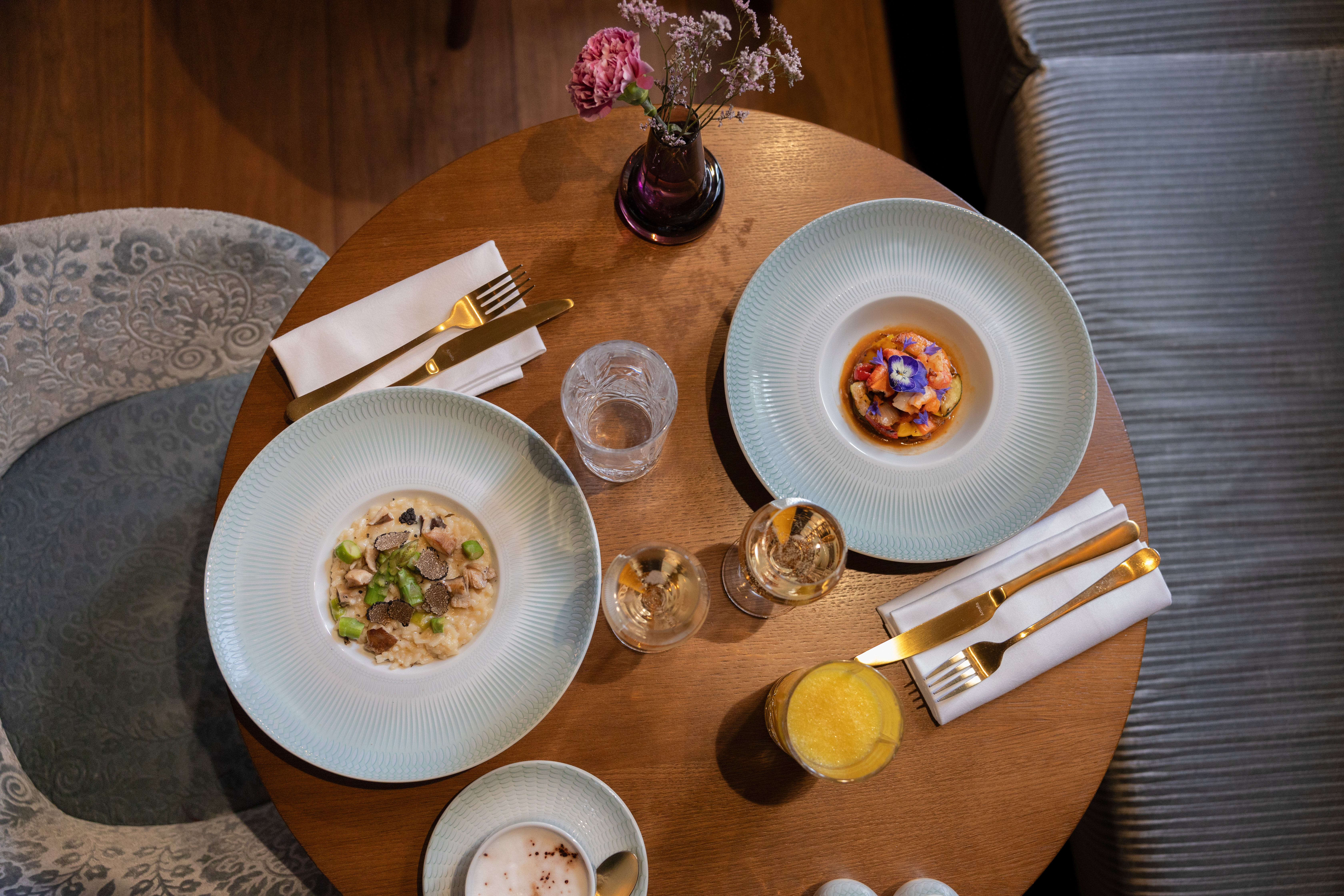 Fine dining: truffle risotto, colorful entree with flowers, drinks on elegant table.