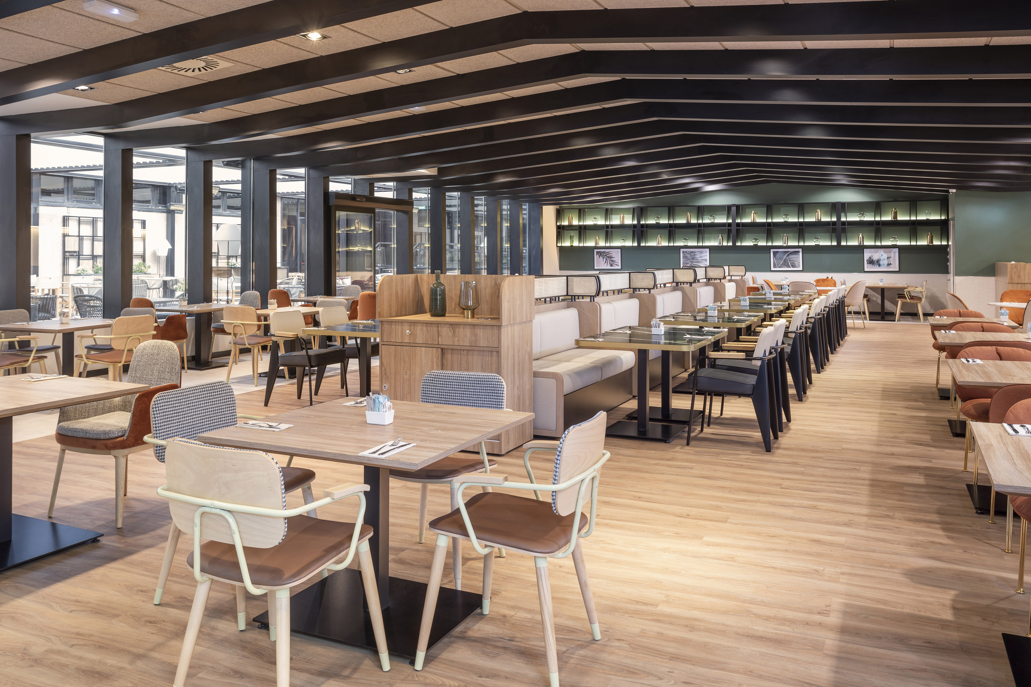 Modern hotel restaurant dining area with wood floors and varied seating.
