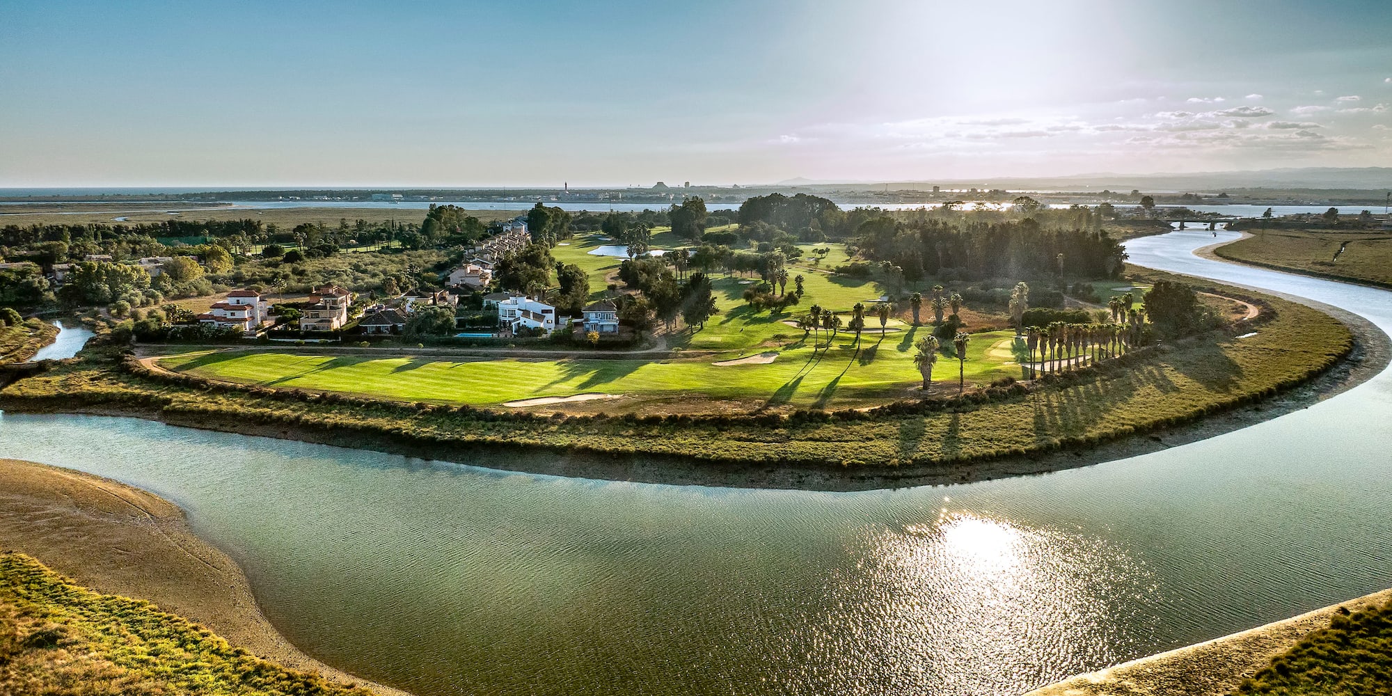 a river with a green field and trees