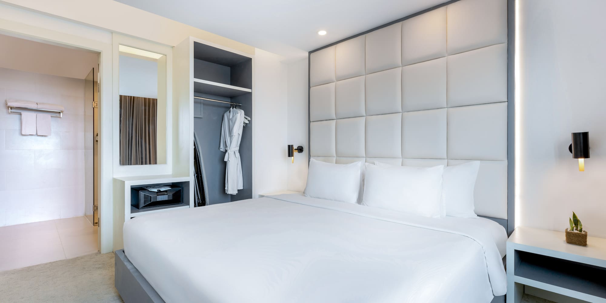 a bed with white sheets and a white robe on a closet