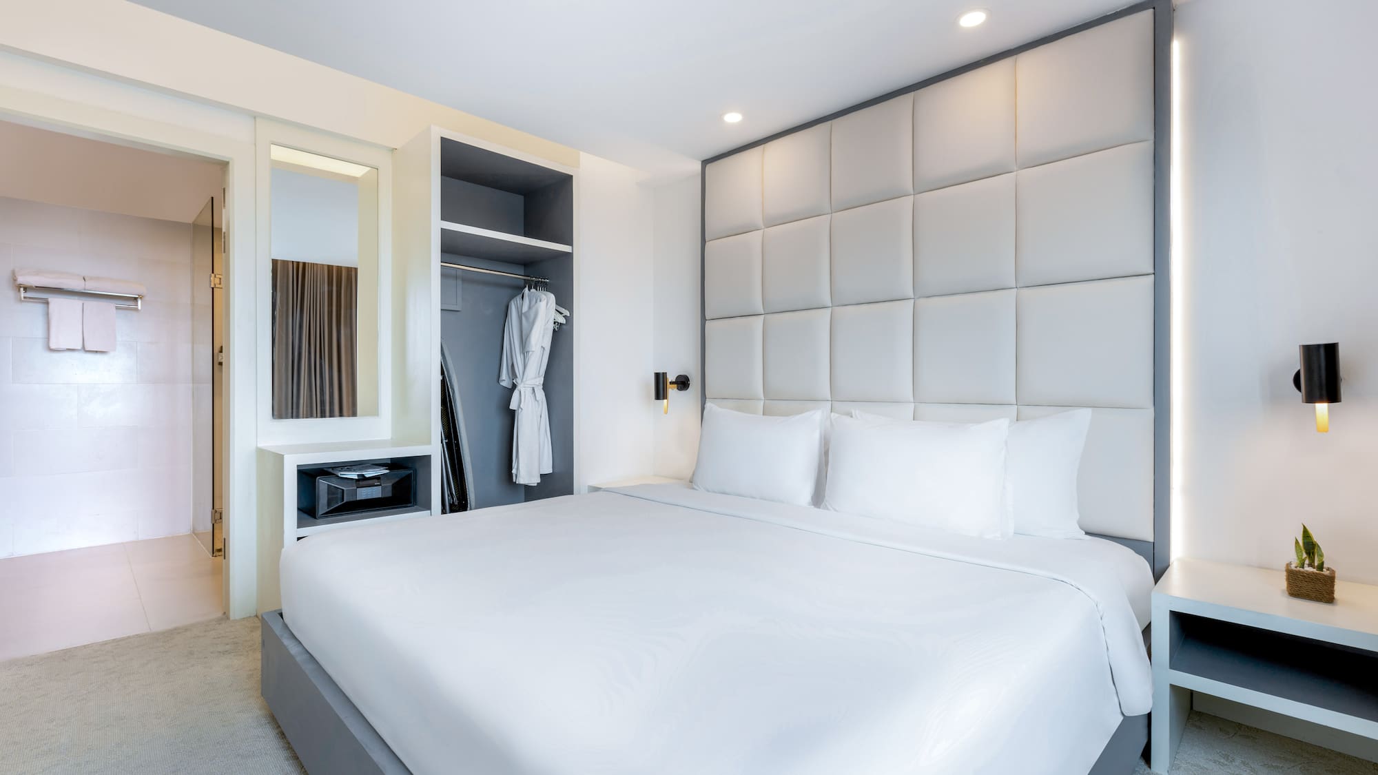 a bed with white sheets and a white robe on a closet