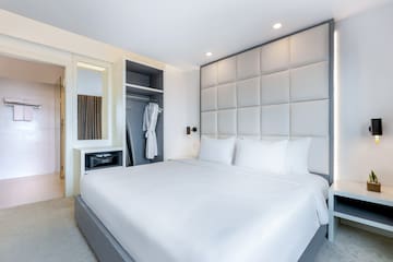 a bed with white sheets and a white robe on a closet