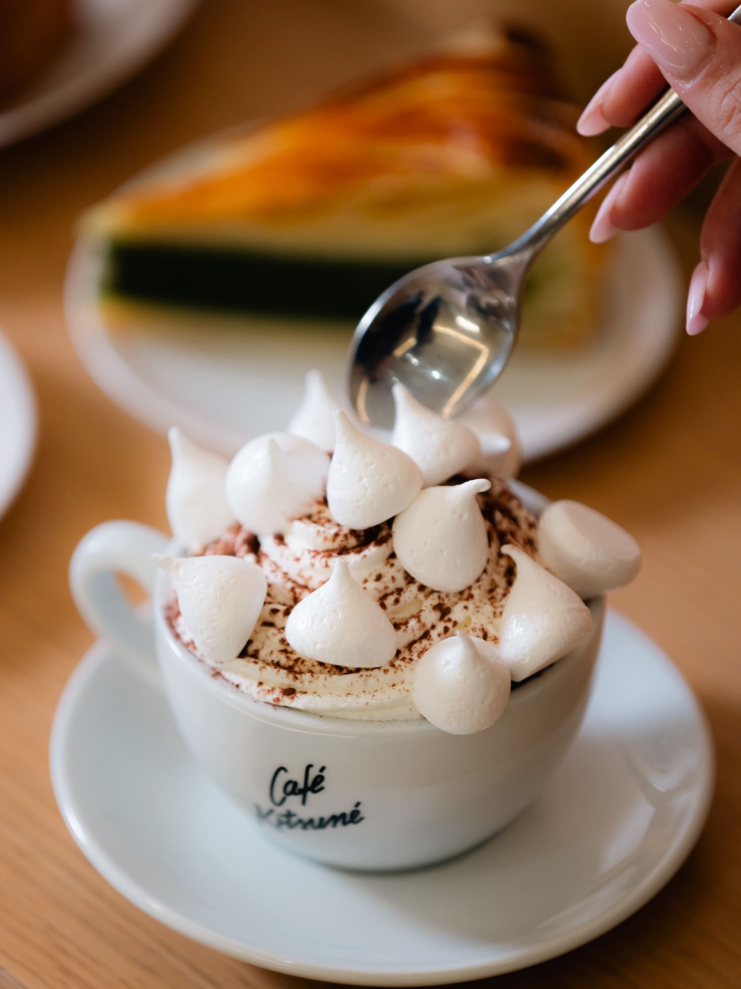 a person pouring whipped cream into a cup of coffee