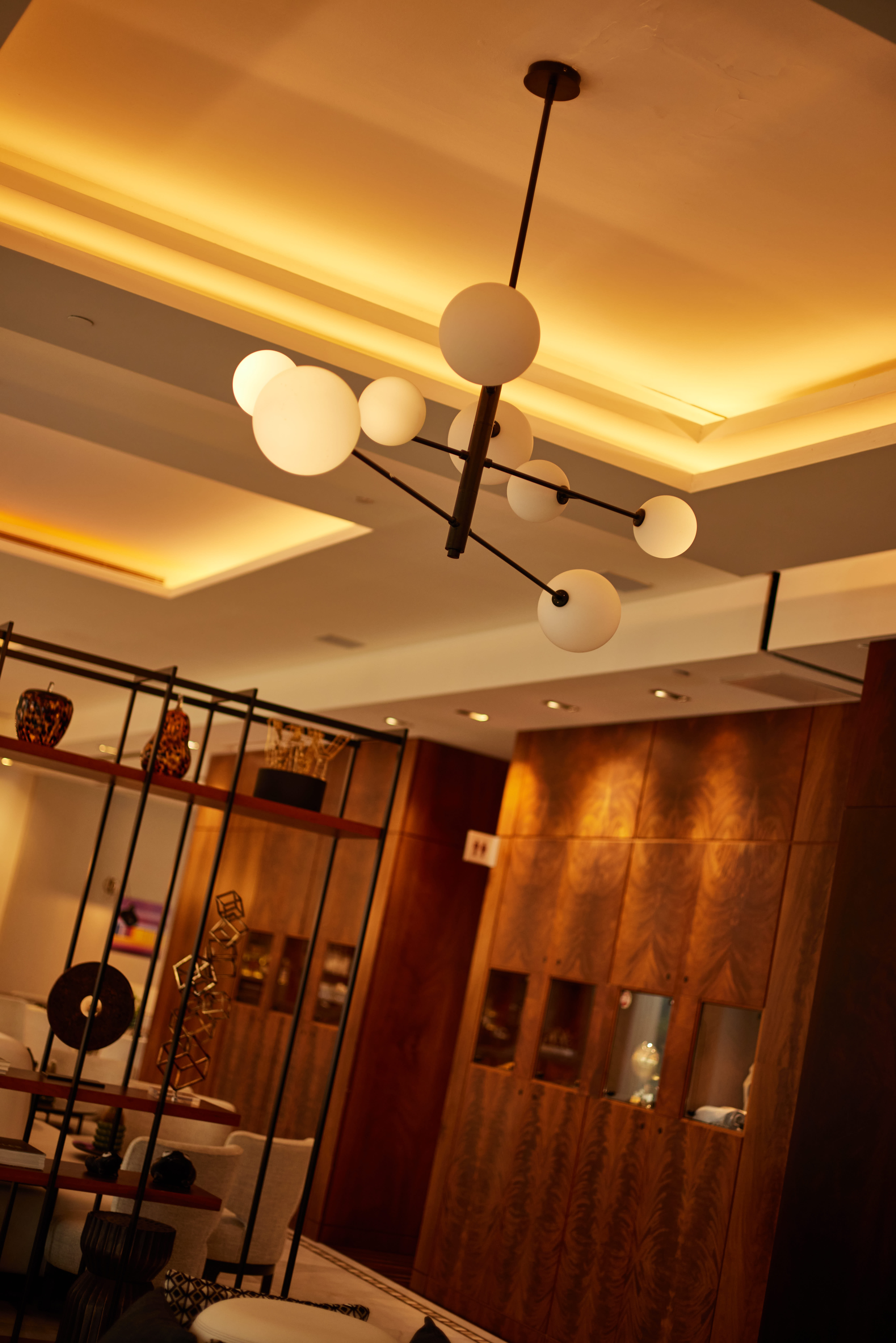Modern spherical chandelier with warm ceiling lighting in a contemporary interior.