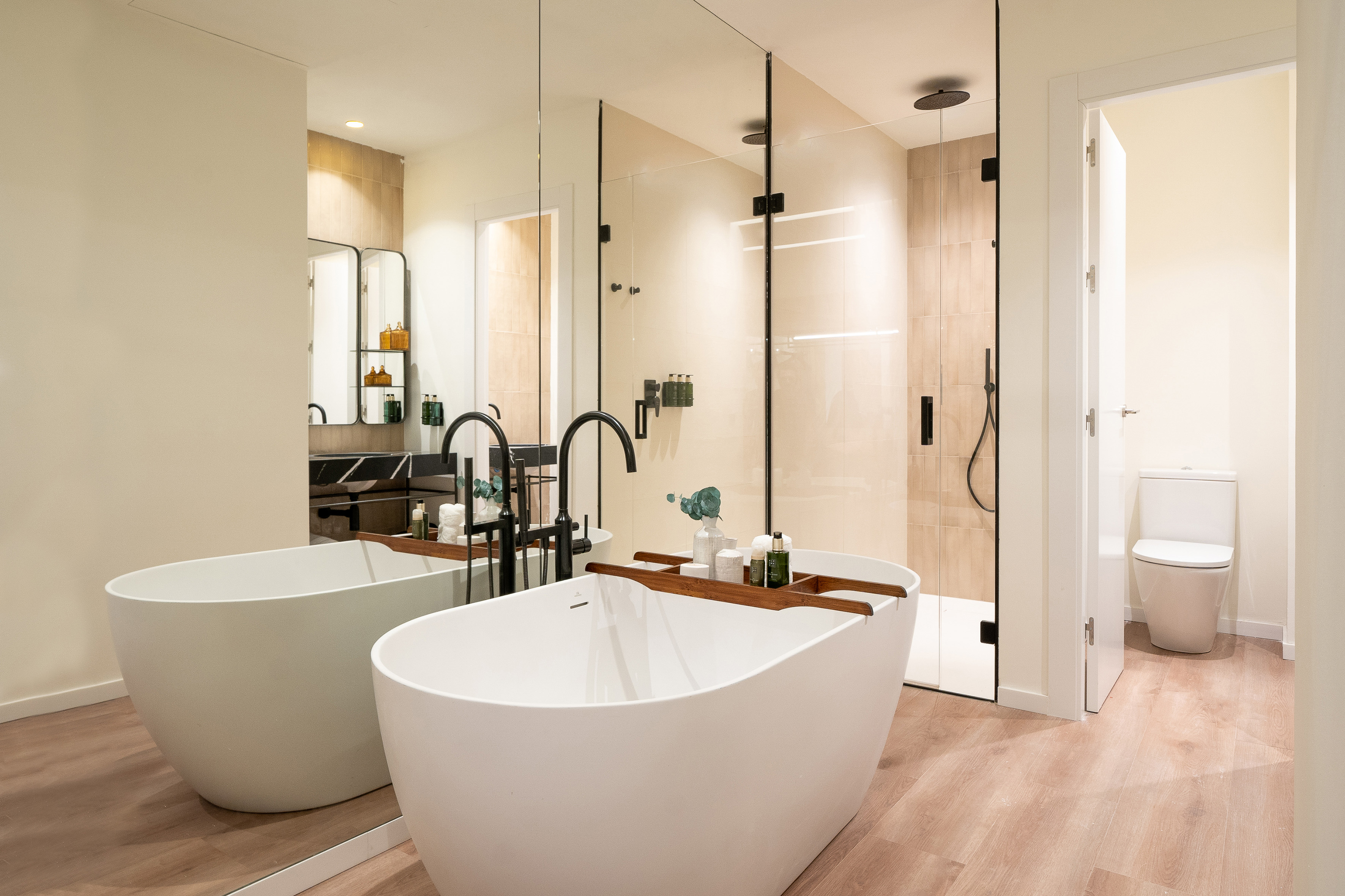 Modern bathroom featuring a freestanding tub, glass shower, and black fixtures.