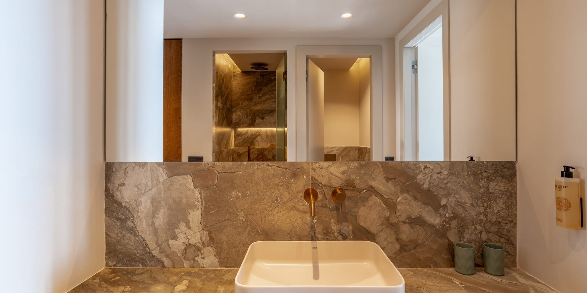 Luxury modern bathroom vanity with marble counter, square sink, gold faucet.
