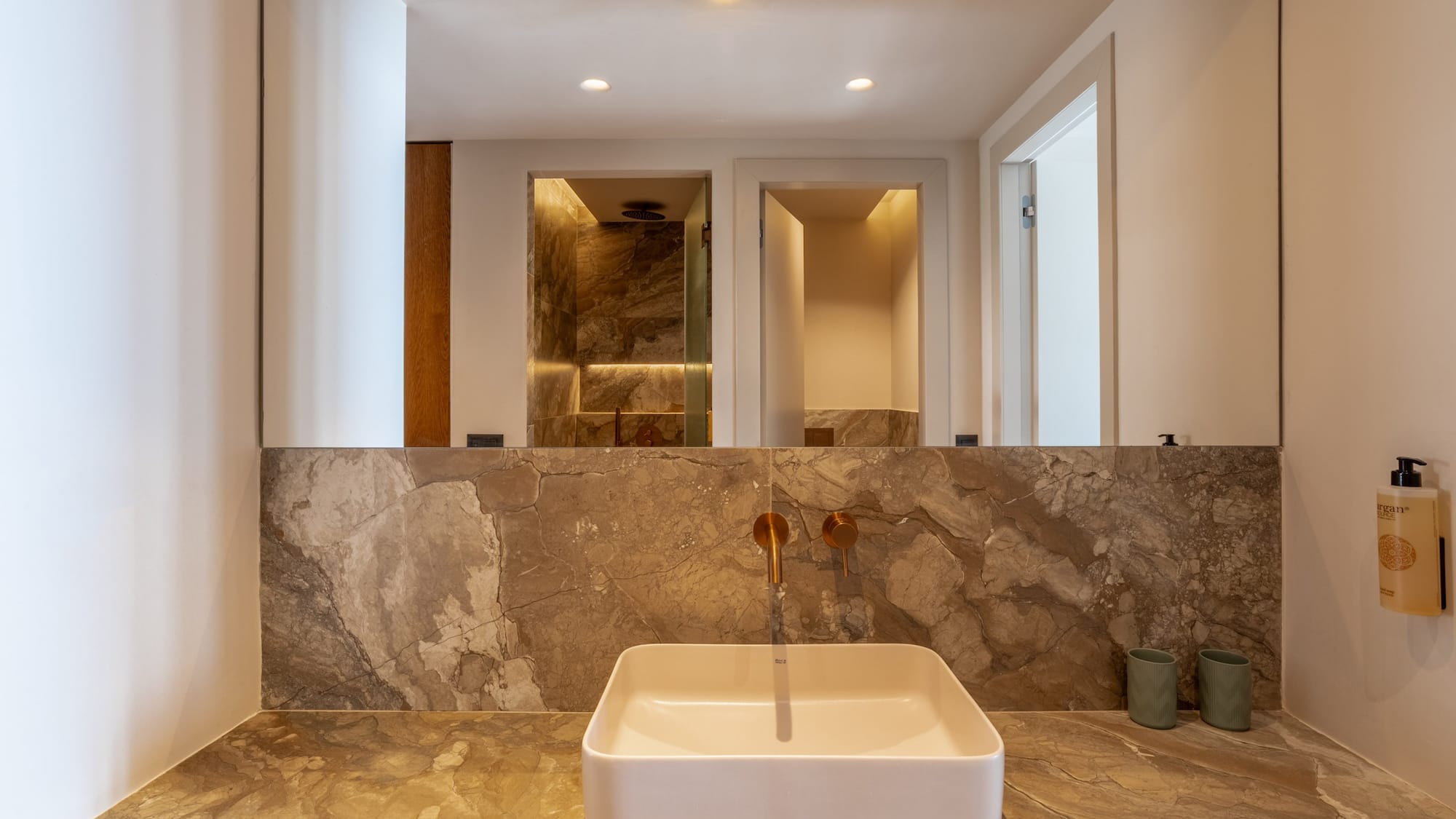Luxury modern bathroom vanity with marble counter, square sink, gold faucet.