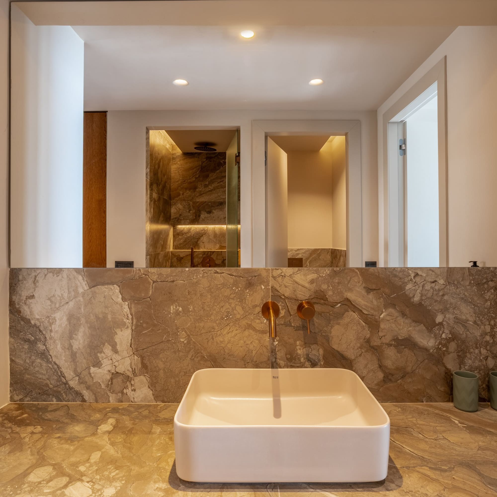 Luxury modern bathroom vanity with marble counter, square sink, gold faucet.