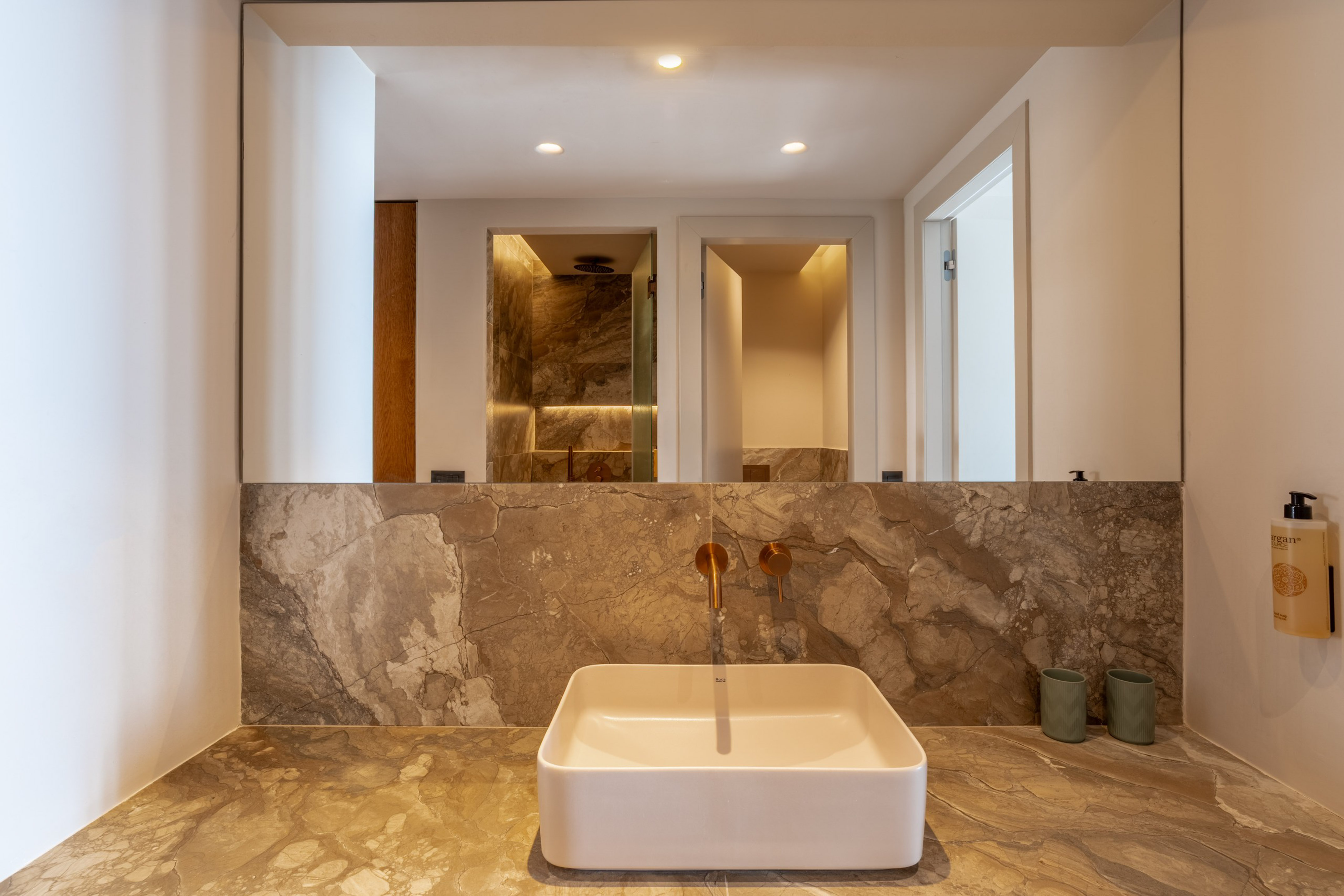 Luxury modern bathroom vanity with marble counter, square sink, gold faucet.