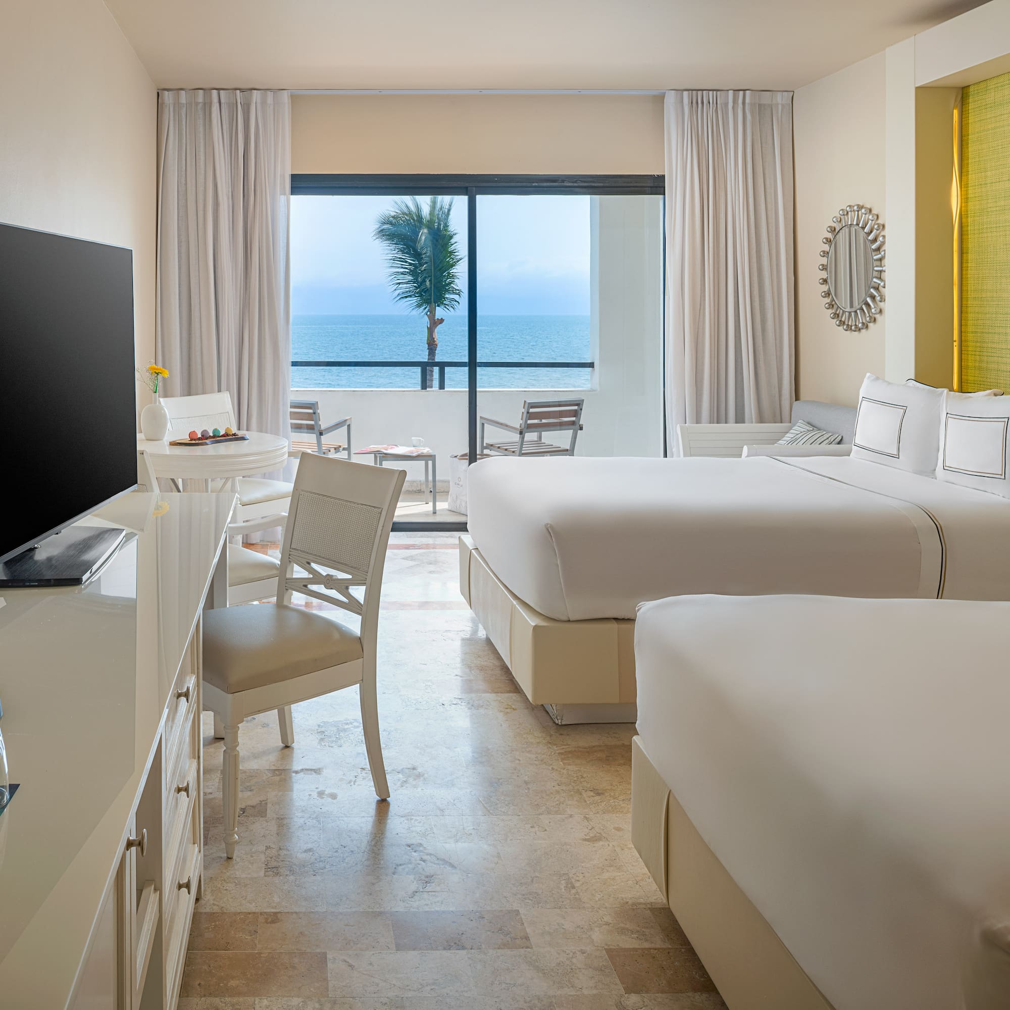 Hotel room with ocean view, two beds, balcony, and coffee machine.