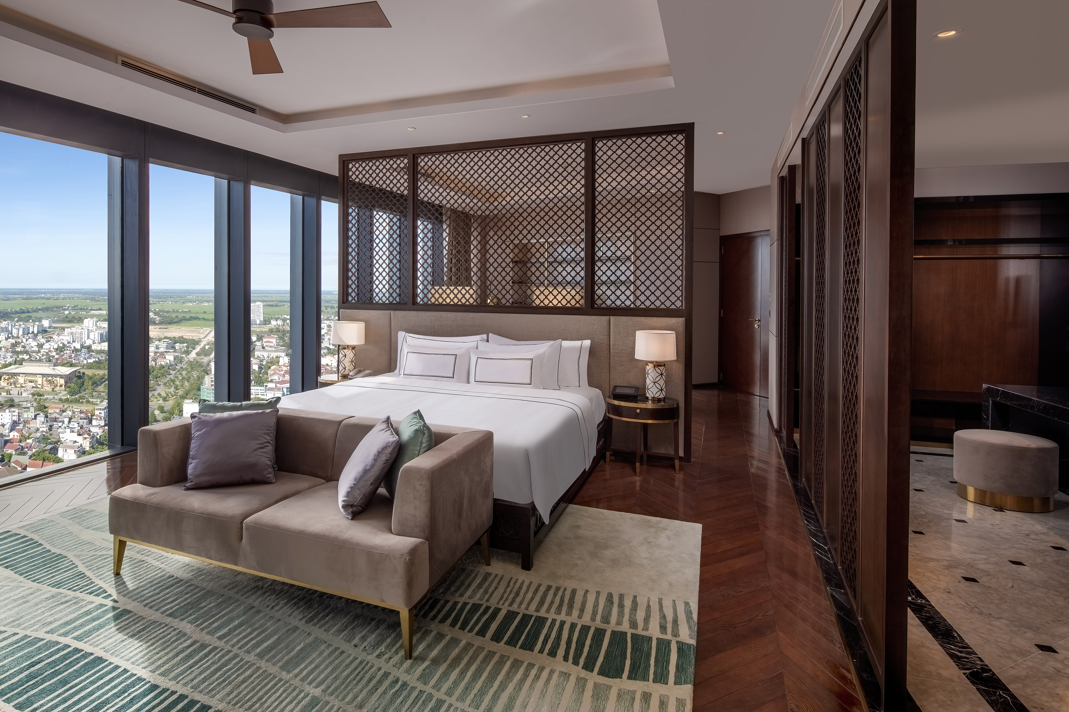 Modern luxury hotel bedroom with panoramic city view and elegant furnishings.