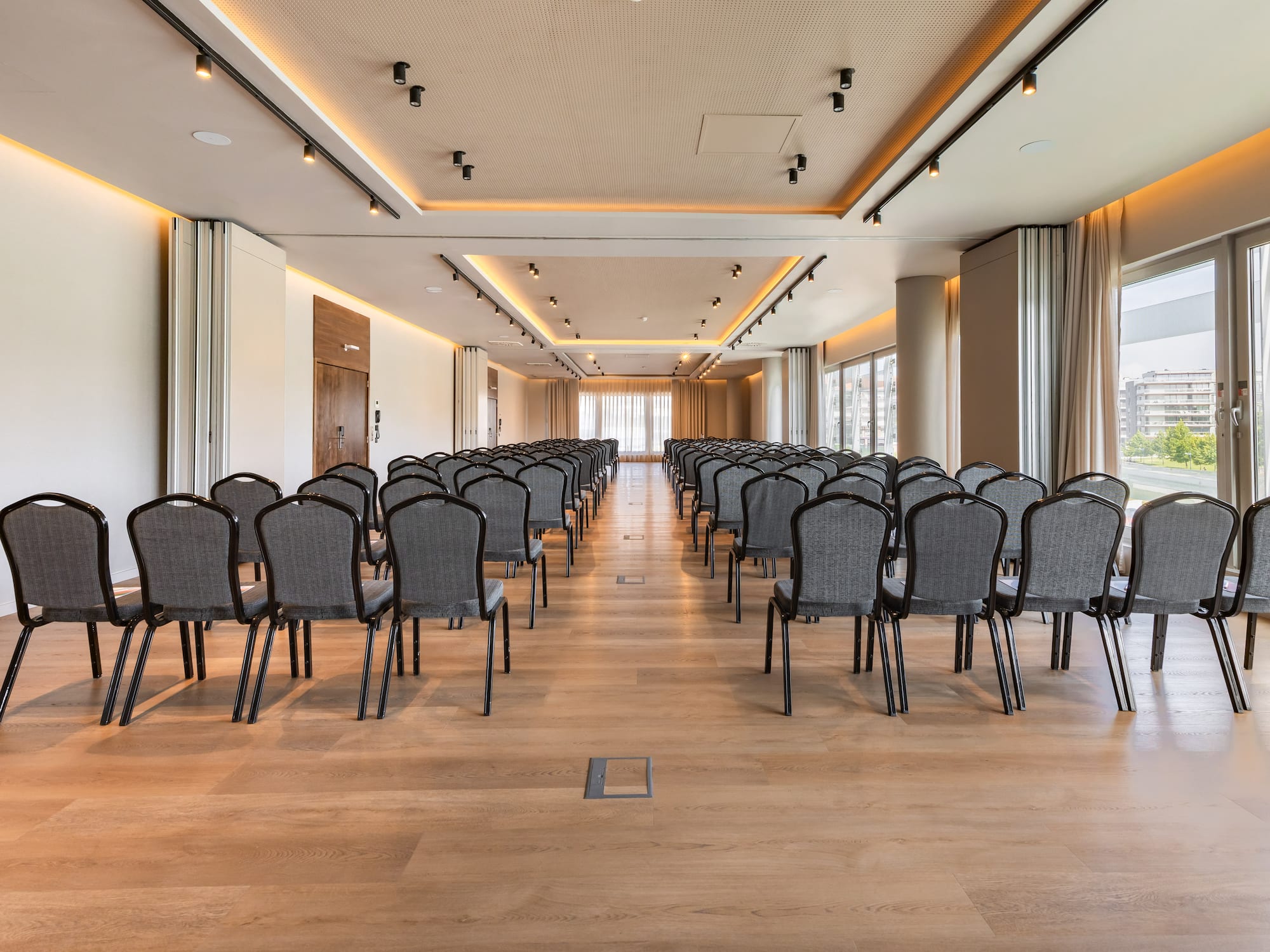 Modern conference room, empty grey chairs, wooden floor, and ambient lighting.