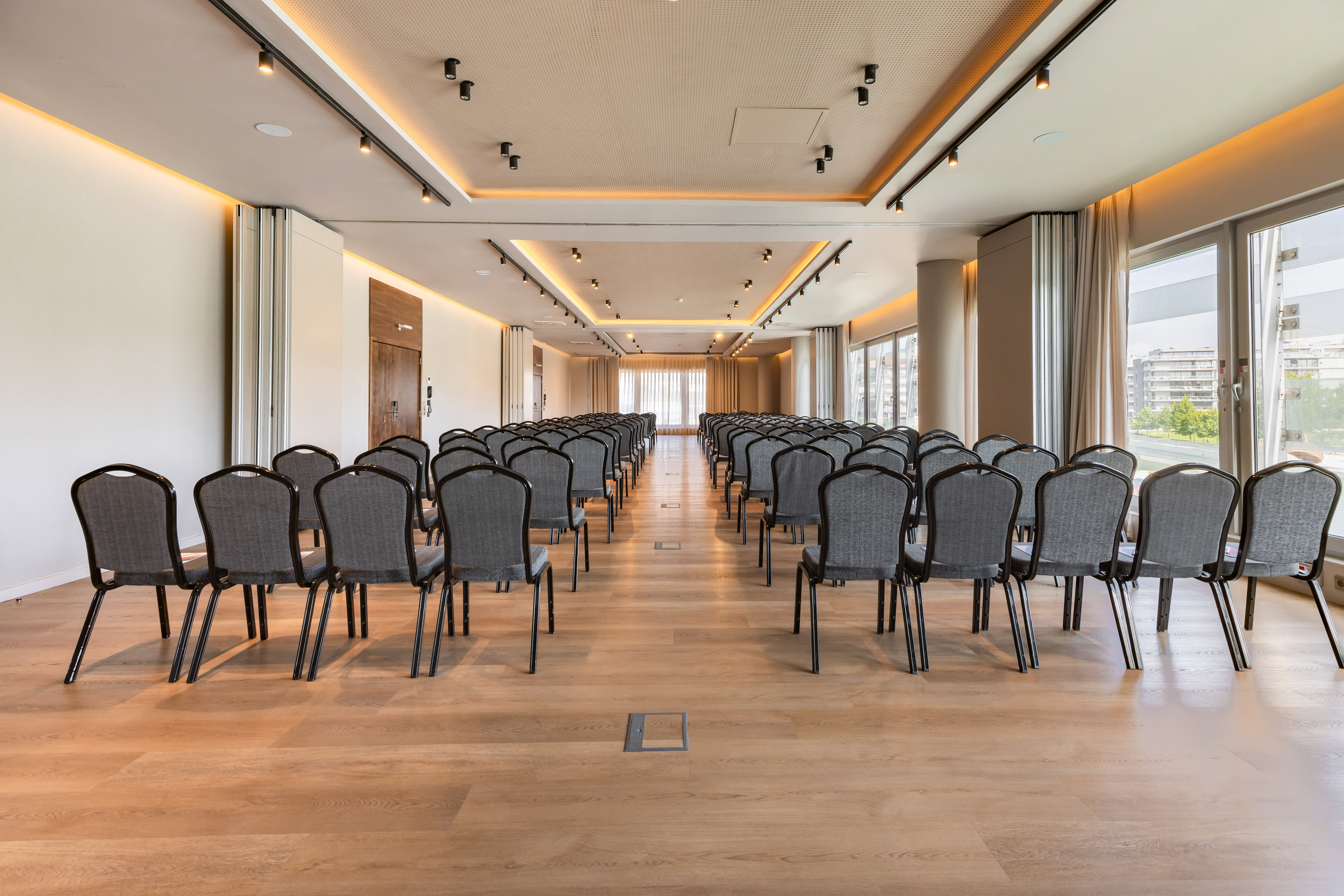Modern conference room, empty grey chairs, wooden floor, and ambient lighting.