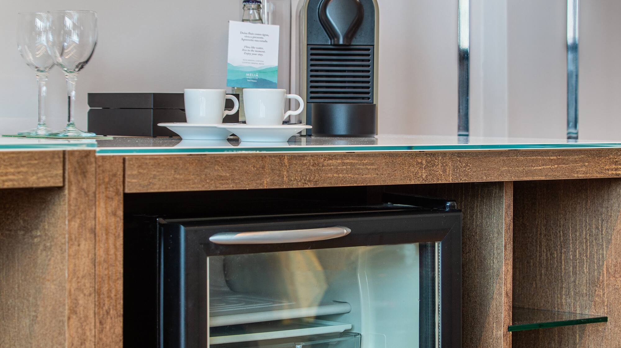 a mini fridge with drinks and cups on top of it