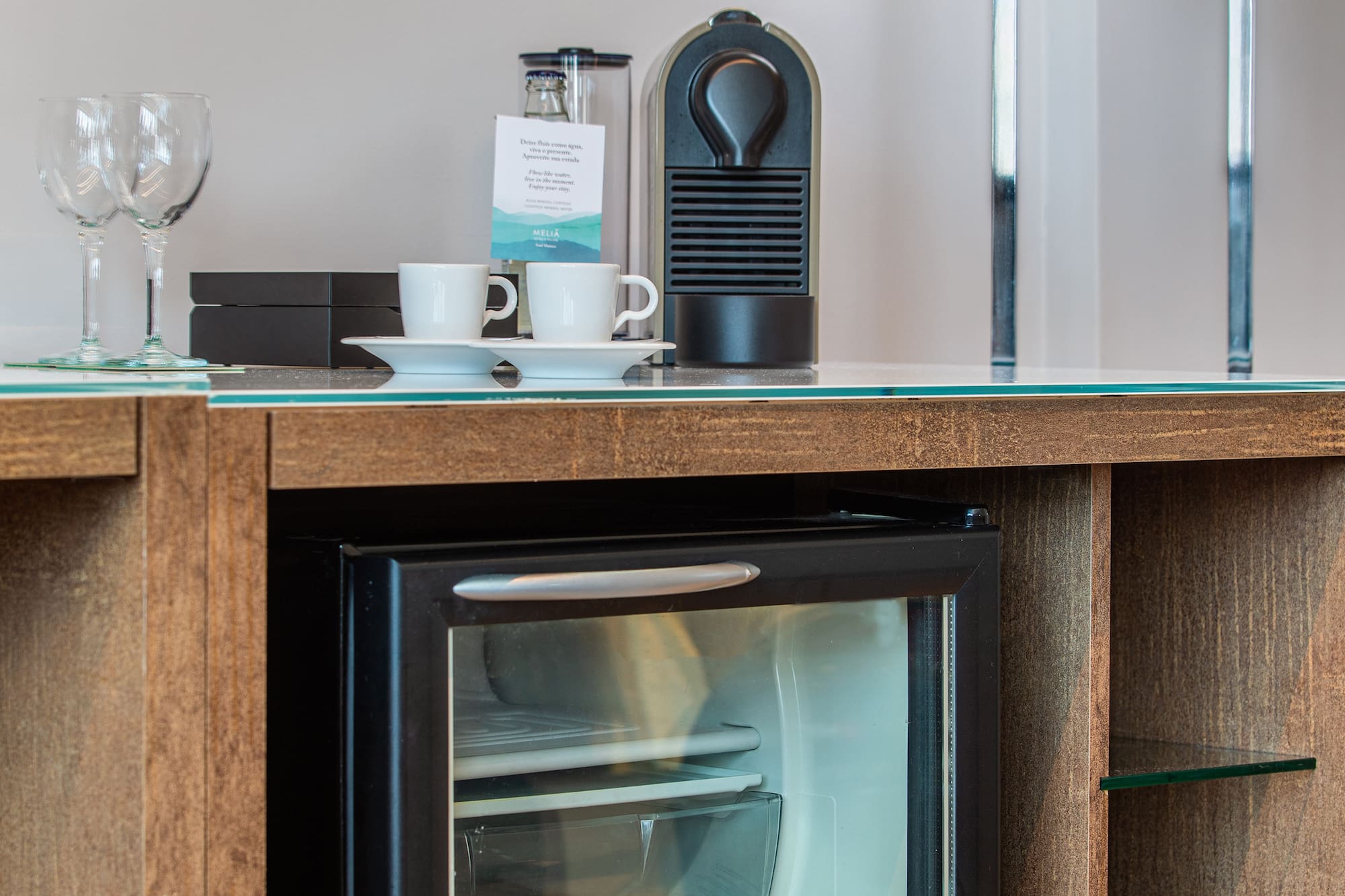 a mini fridge with drinks and cups on top of it