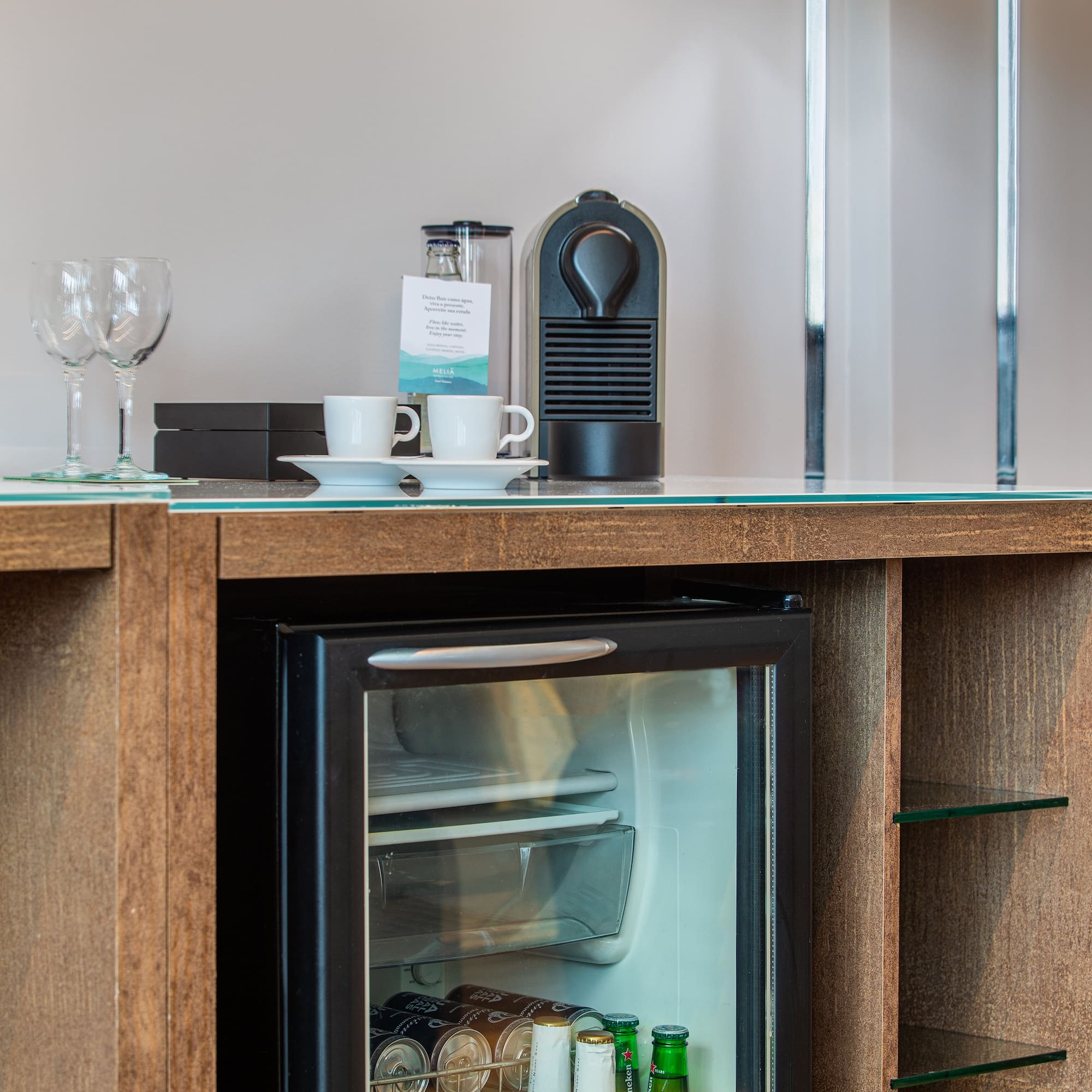 a mini fridge with drinks and cups on top of it