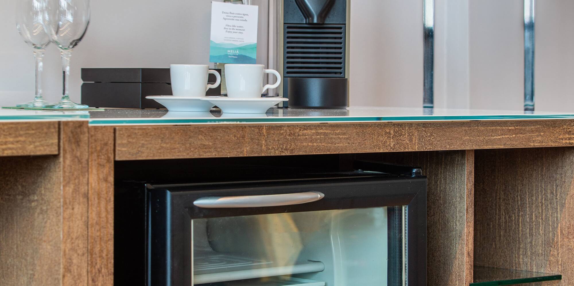a mini fridge with drinks and cups on top of it