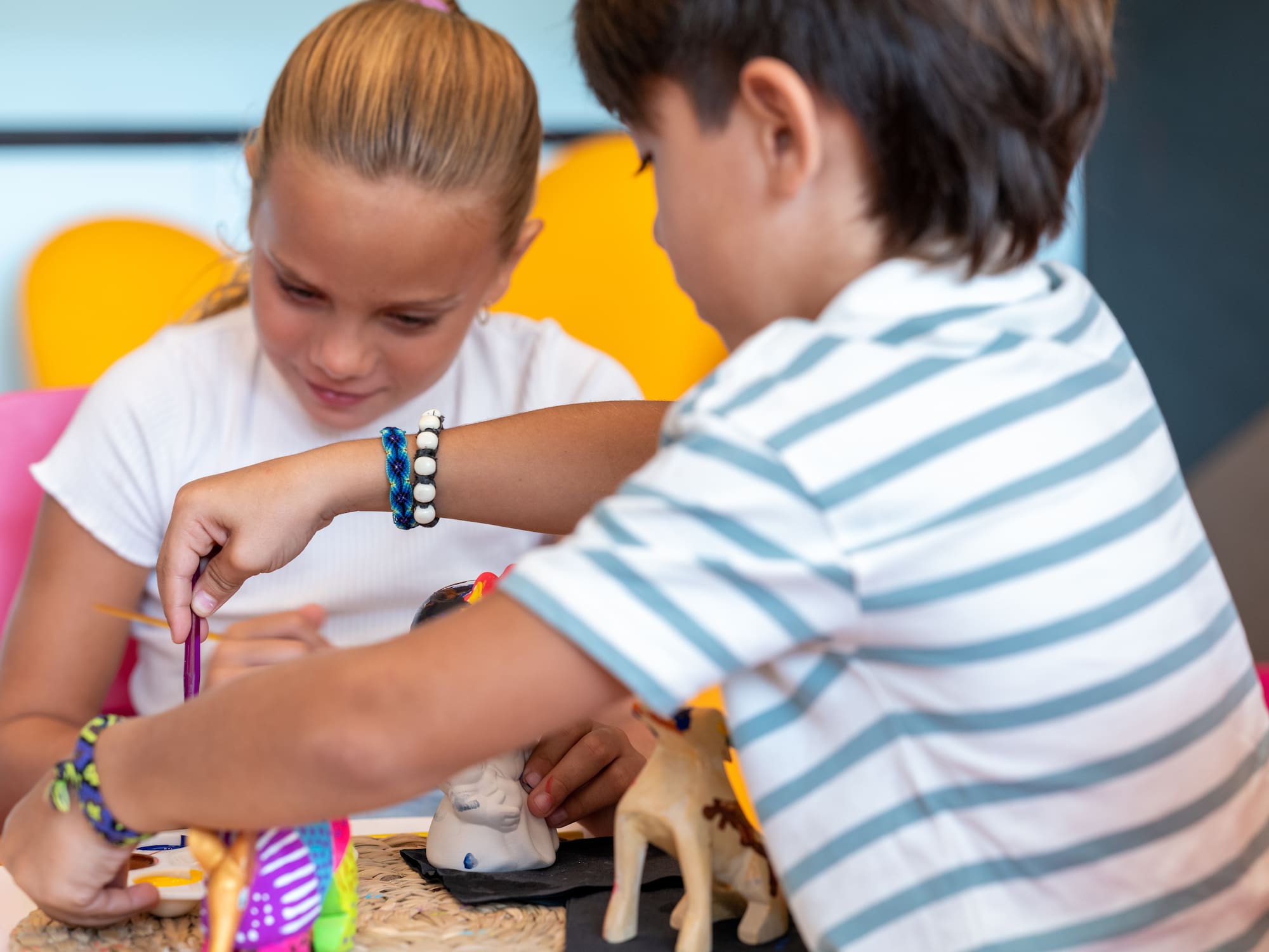 a boy and girl painting on a toy elephant