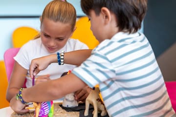 a boy and girl painting on a toy elephant
