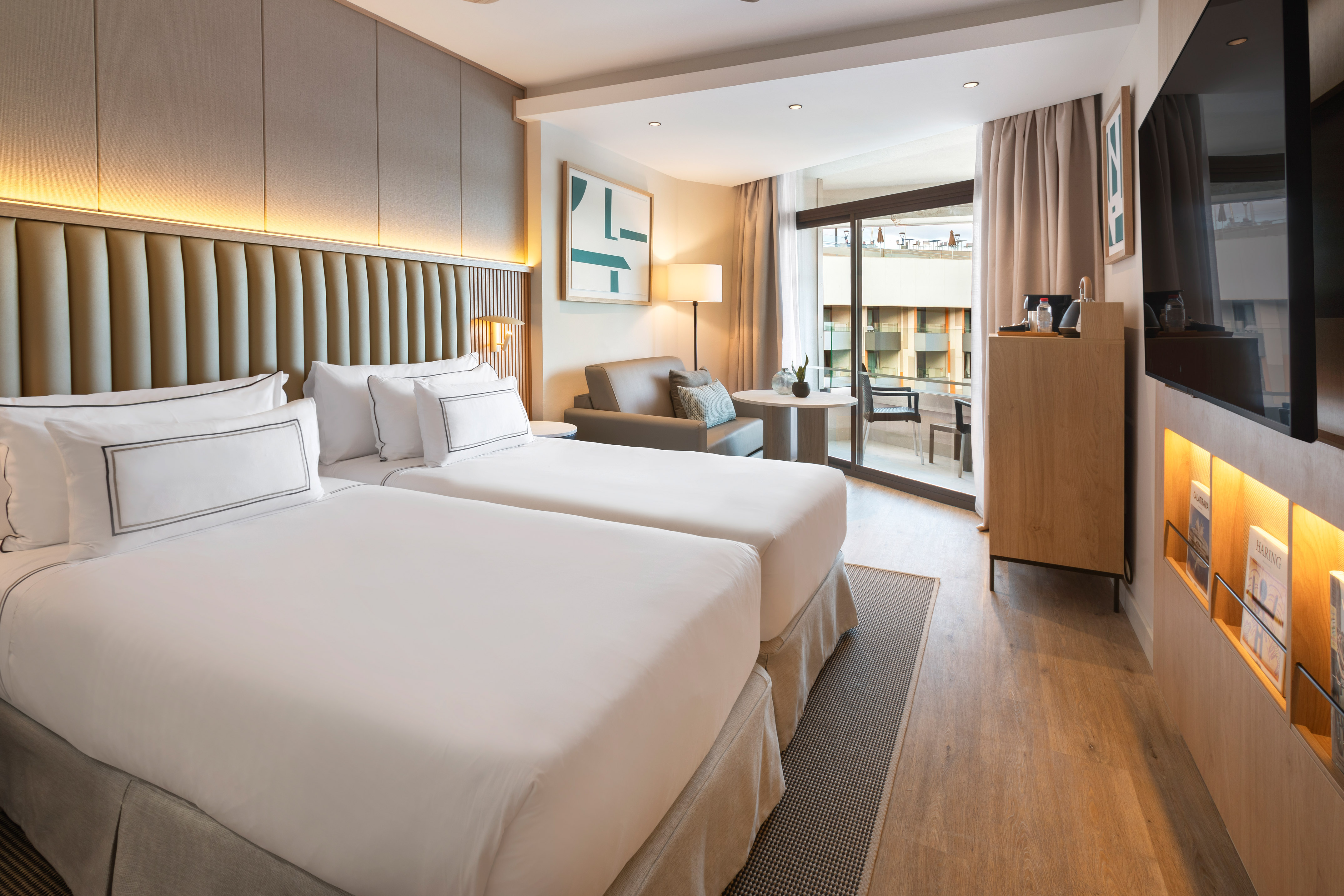 Modern hotel room with twin beds, balcony, and contemporary design.