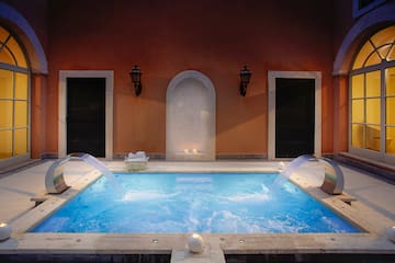 a pool with water jets and a couple of chairs