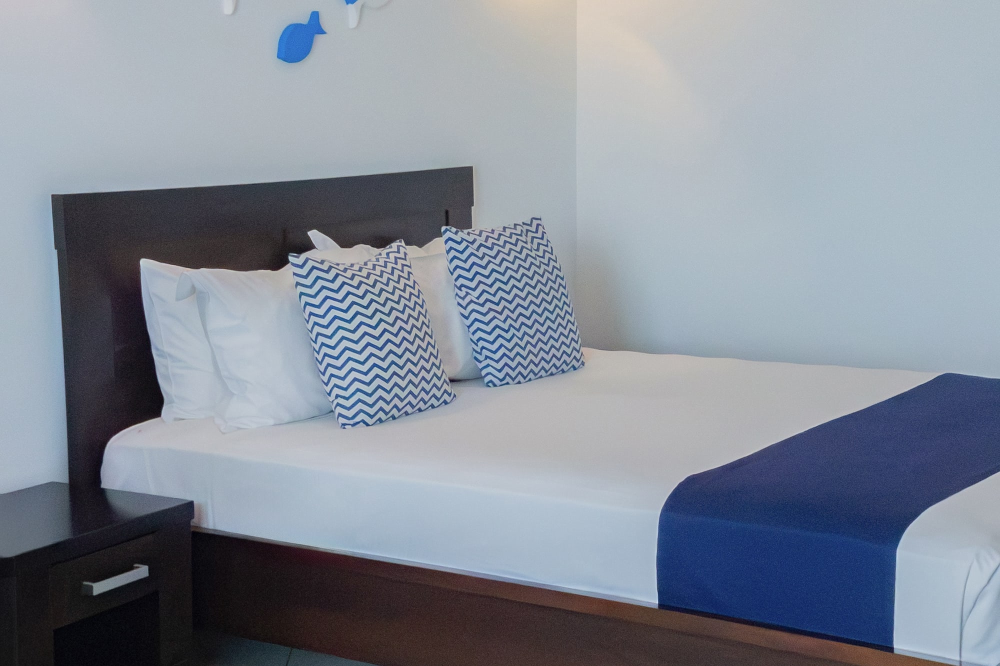 a bed with pillows and a nightstand in a room with fish decorations