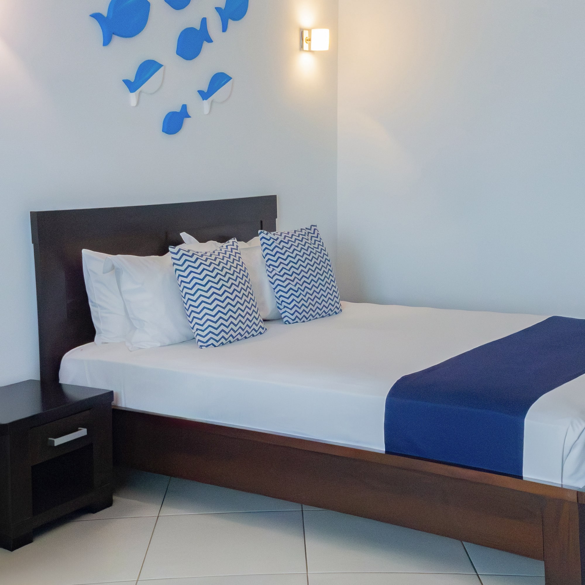 a bed with pillows and a nightstand in a room with fish decorations