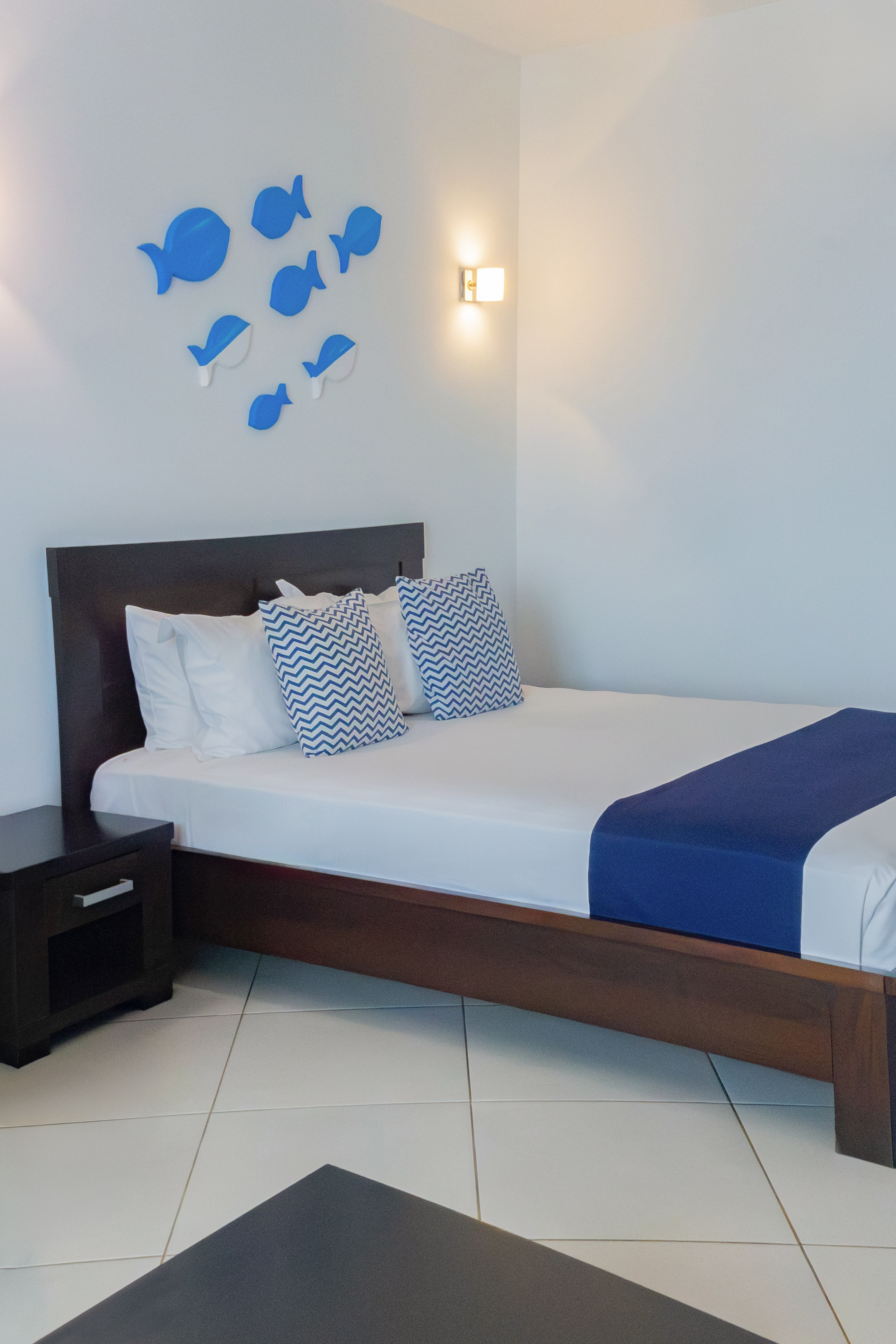 a bed with pillows and a nightstand in a room with fish decorations