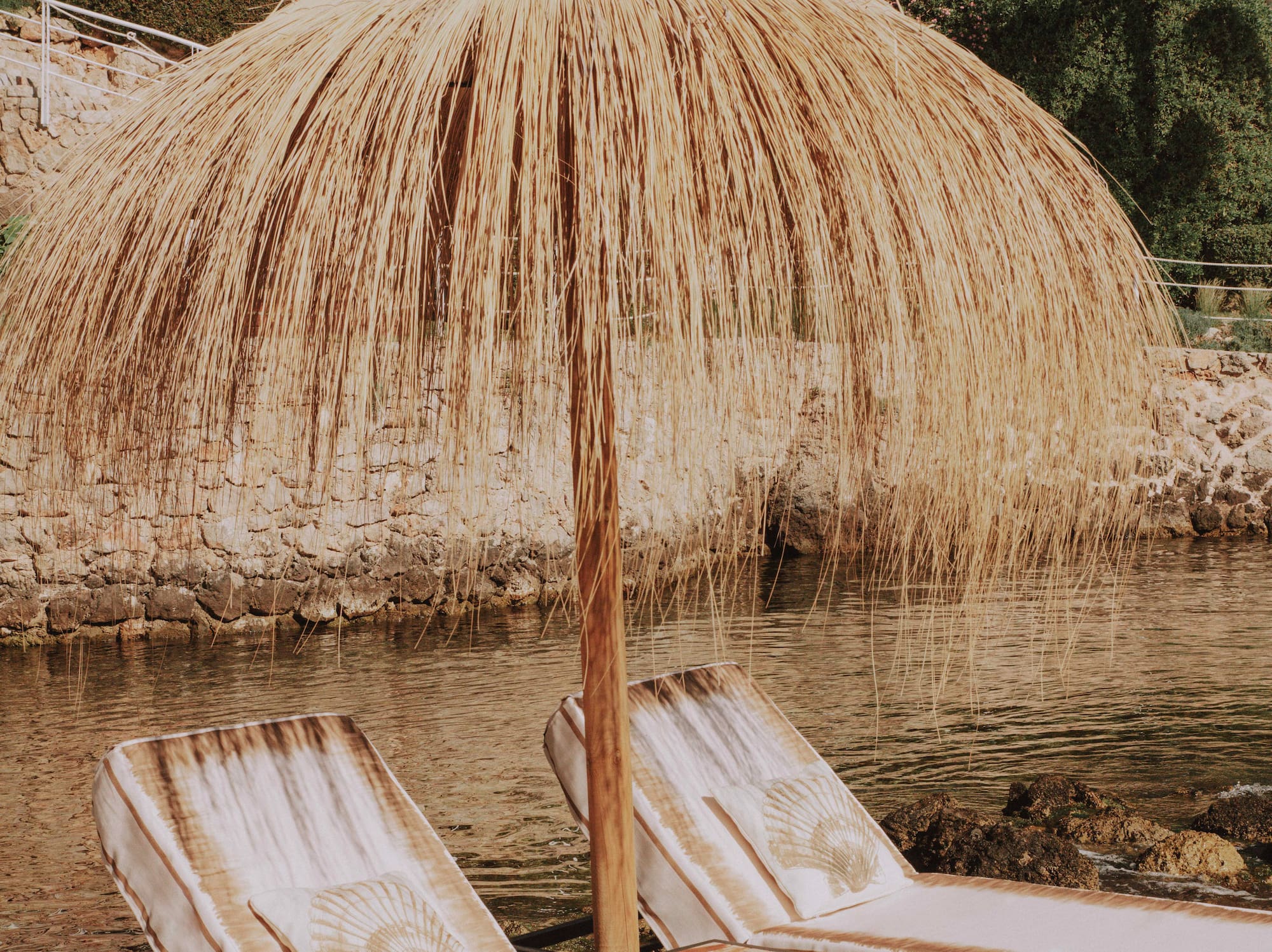 two chairs and umbrella on a body of water