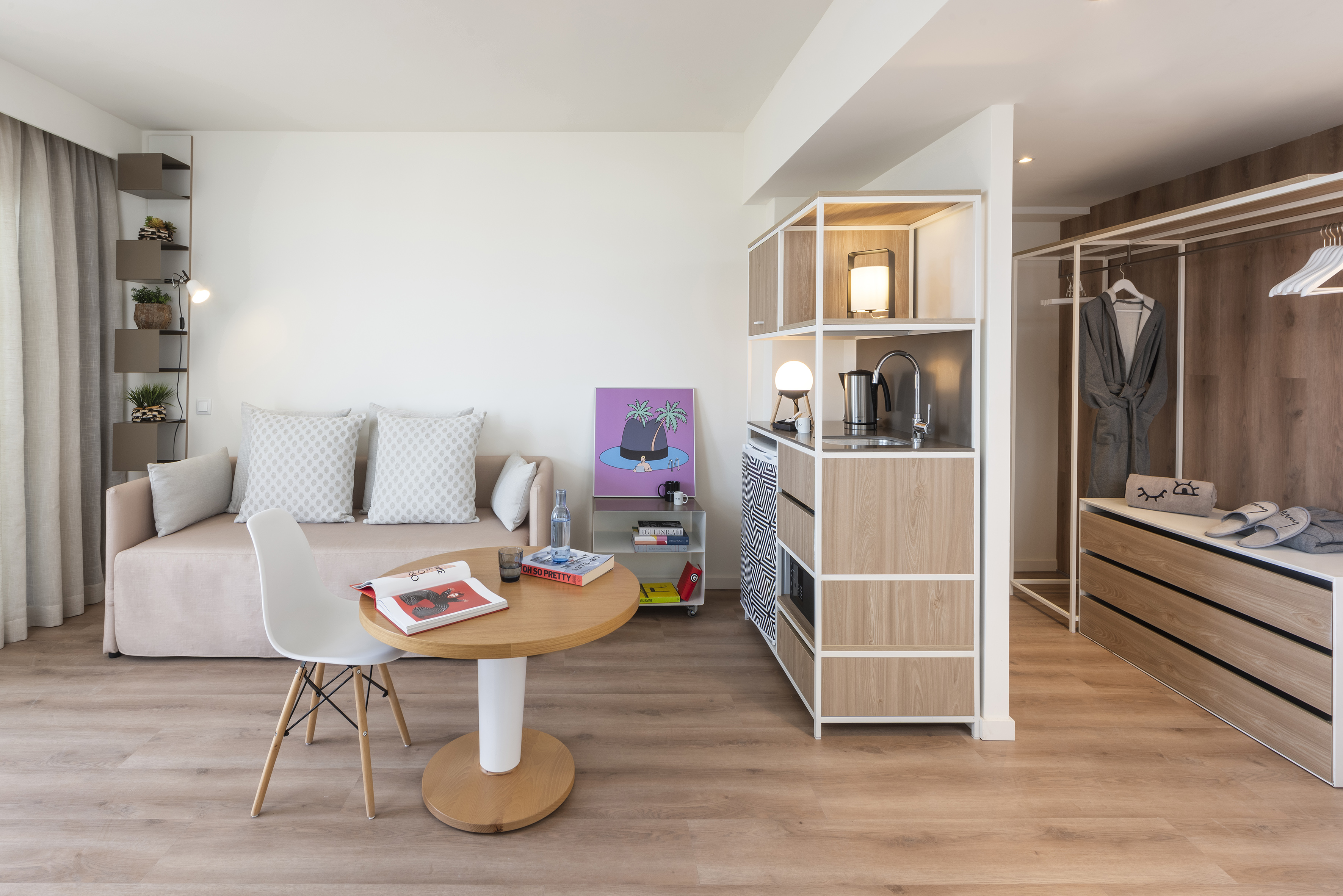 Cozy studio apartment with sofa, dining table, kitchen counter, and open closet.
