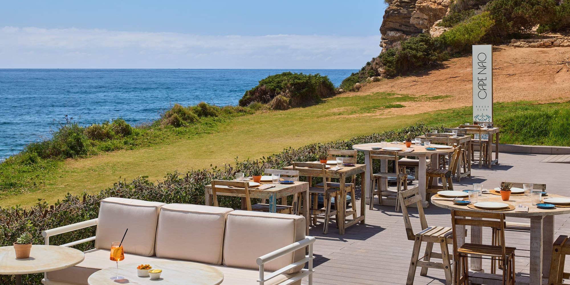 a outdoor restaurant with tables and chairs on a deck overlooking the ocean