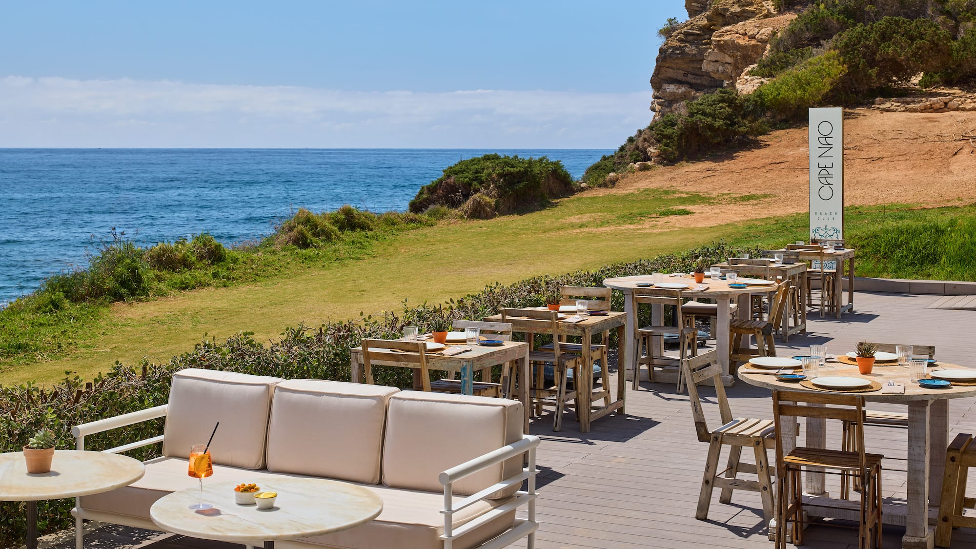 a outdoor restaurant with tables and chairs on a deck overlooking the ocean