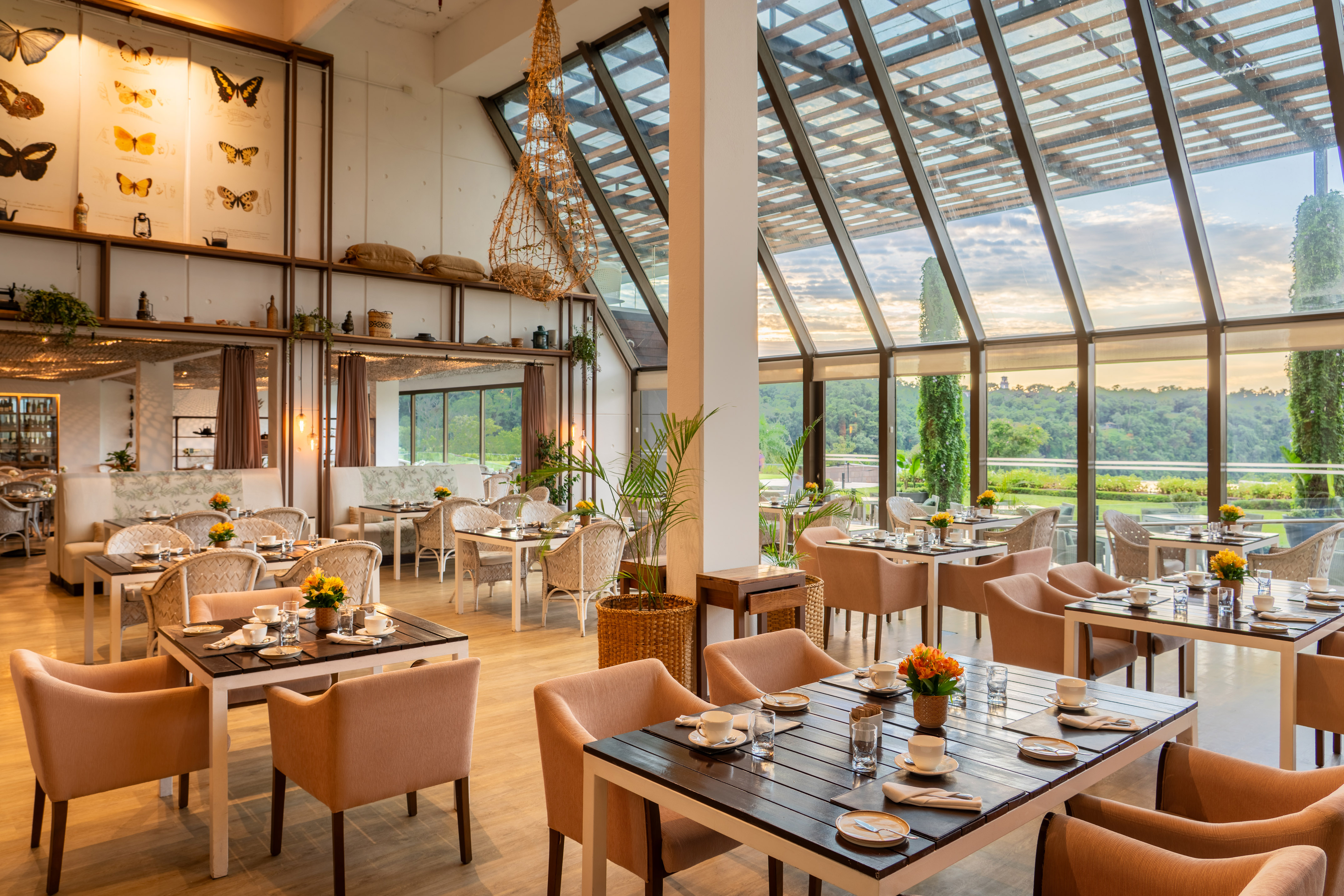 Elegant hotel restaurant with modern glass architecture and lush nature view.