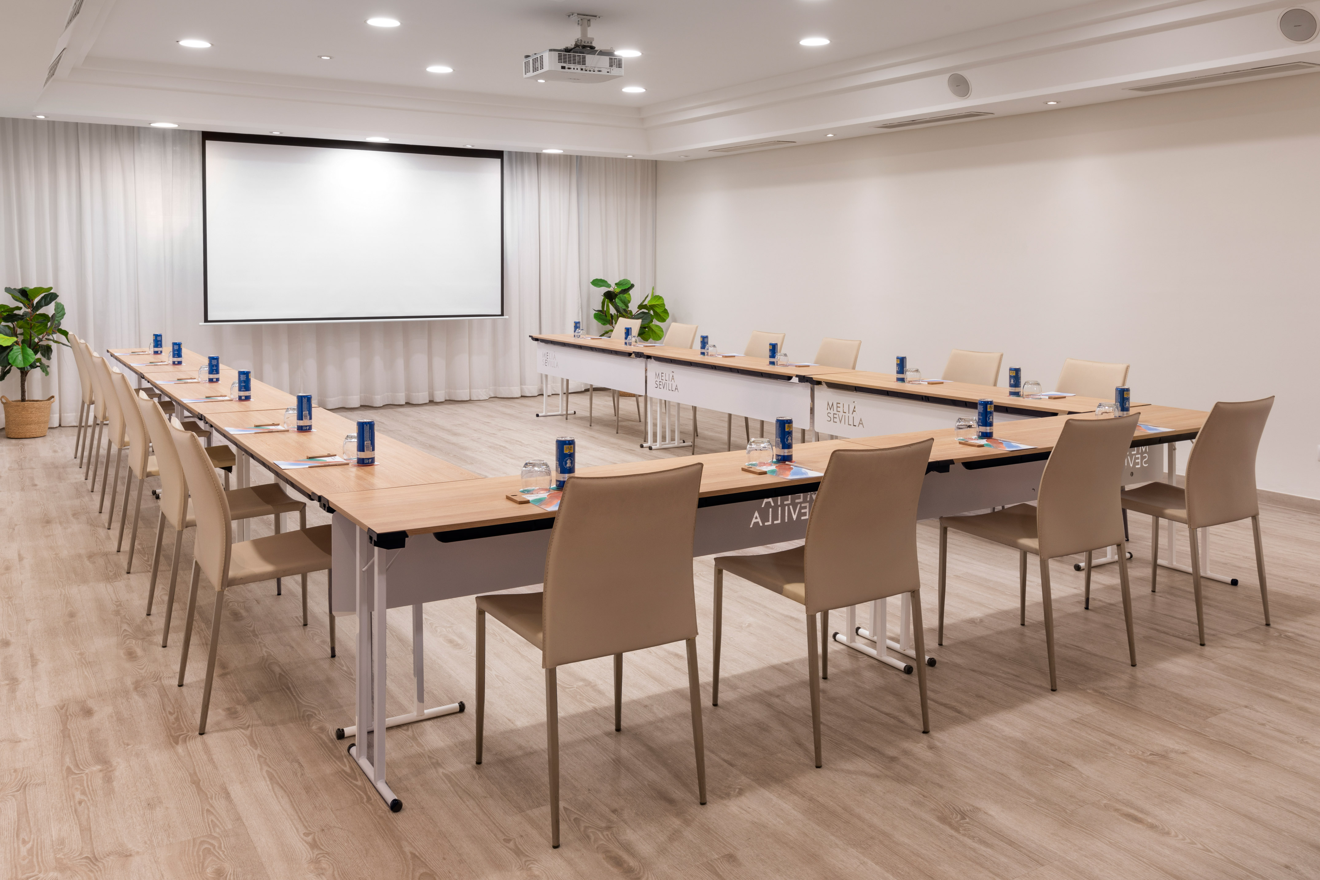 Meliá Sevilla U-shaped meeting room with projector screen and tables.